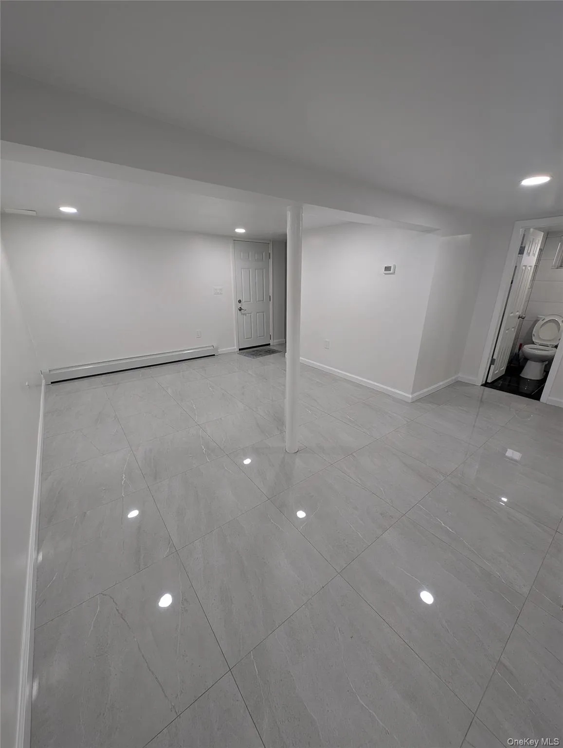 Basement with a baseboard radiator, recessed lighting, marble finish floor, and baseboards Basement with a baseboard radiator, recessed lighting, marble finish floor, and baseboards