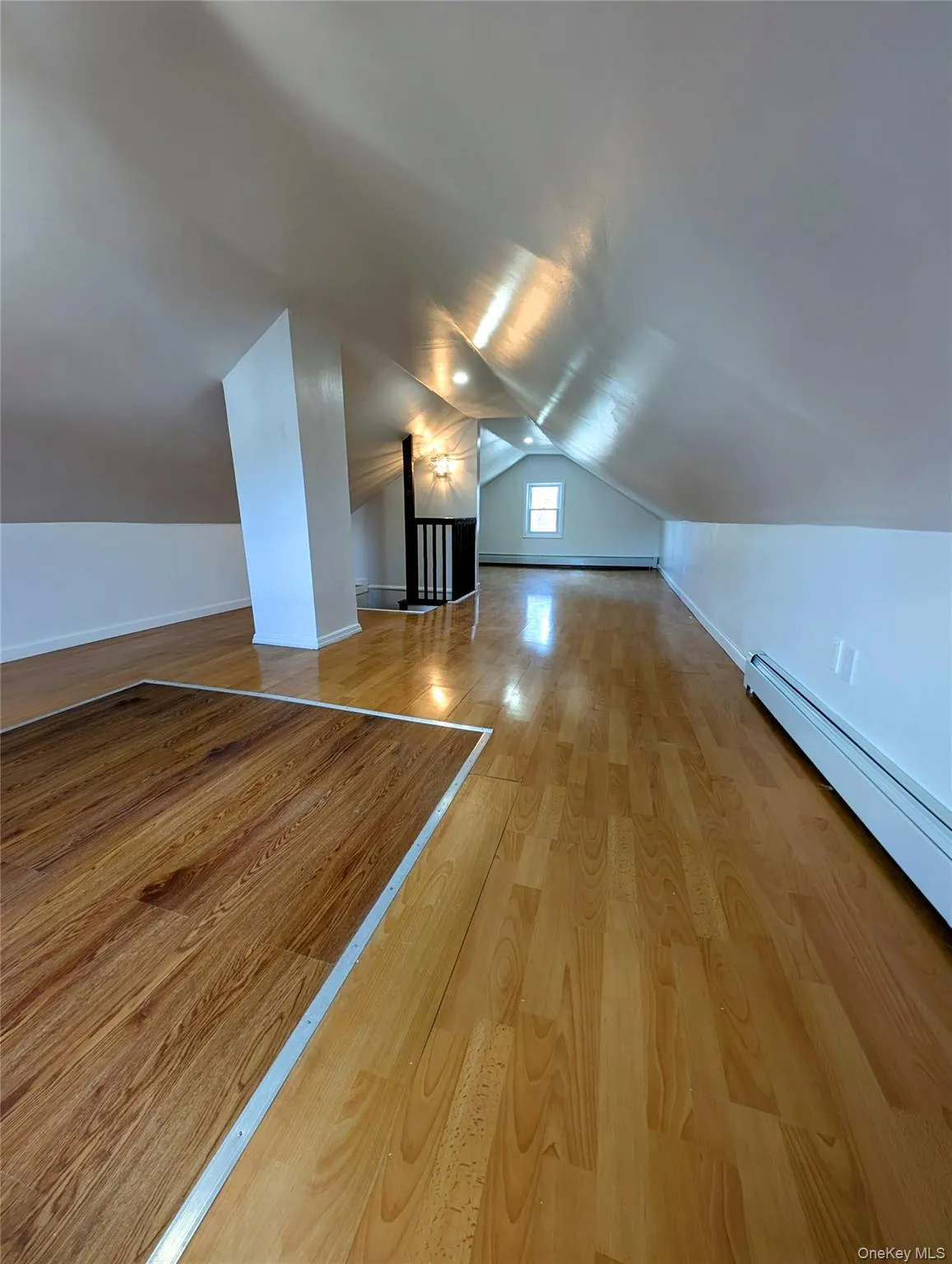 Additional living space featuring baseboards, a baseboard heating unit, vaulted ceiling, and wood finished floors Additional living space featuring baseboards, a baseboard heating unit, vaulted ceiling, and wood finished floors