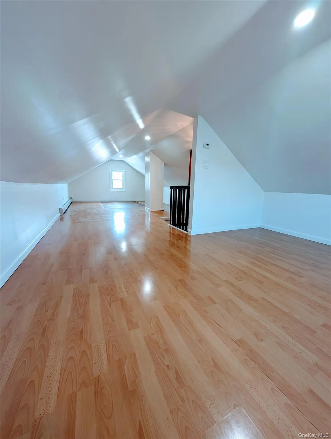 Additional living space with baseboards, vaulted ceiling, and wood finished floors Additional living space with baseboards, vaulted ceiling, and wood finished floors
