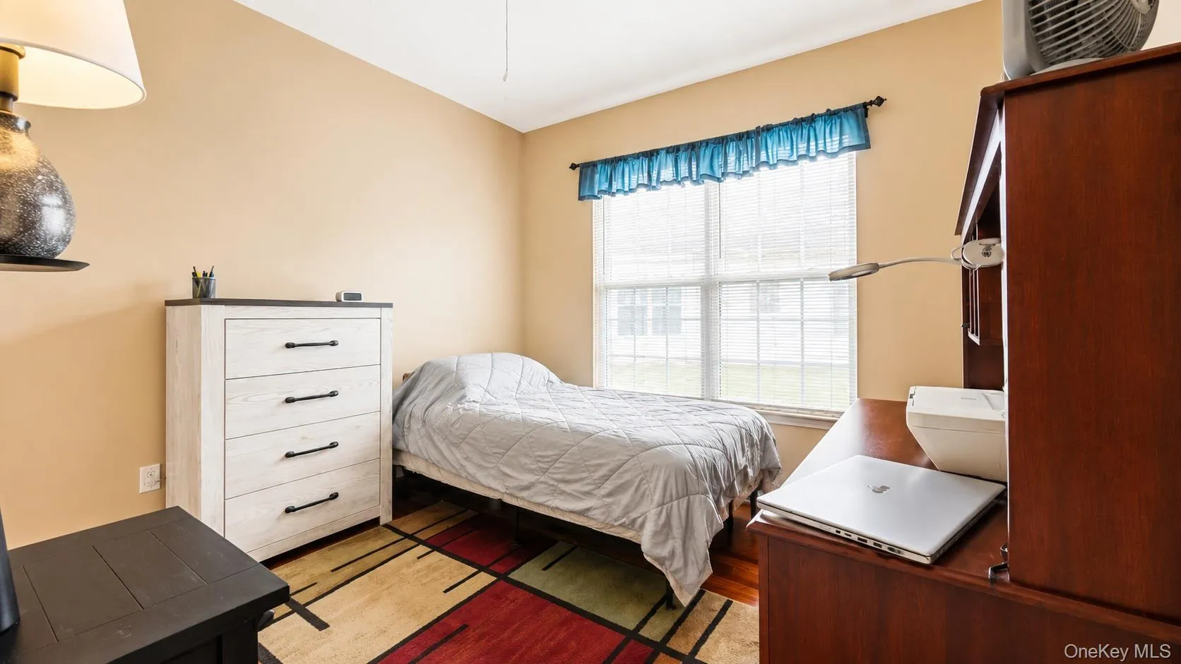 Neutral wall tones, wood-finish flooring, and a large window with horizontal blinds Neutral wall tones, wood-finish flooring, and a large window with horizontal blinds