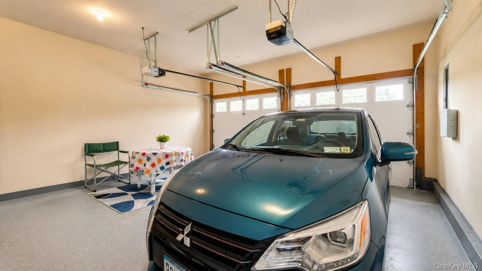 Attached two-car garage featuring automatic door openers, a light-colored painted floor, and multiple windows in the garage doors Attached two-car garage featuring automatic door openers, a light-colored painted floor, and multiple windows in the garage doors