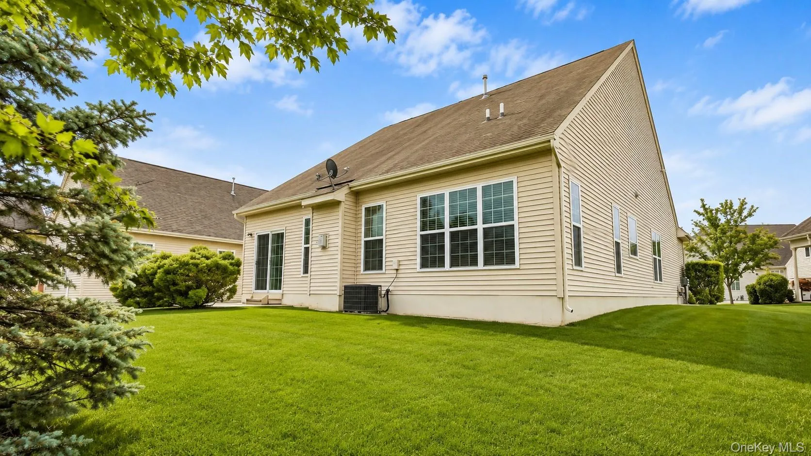 Expansive green lawn, light-colored siding, multiple windows, and a sliding glass door Expansive green lawn, light-colored siding, multiple windows, and a sliding glass door