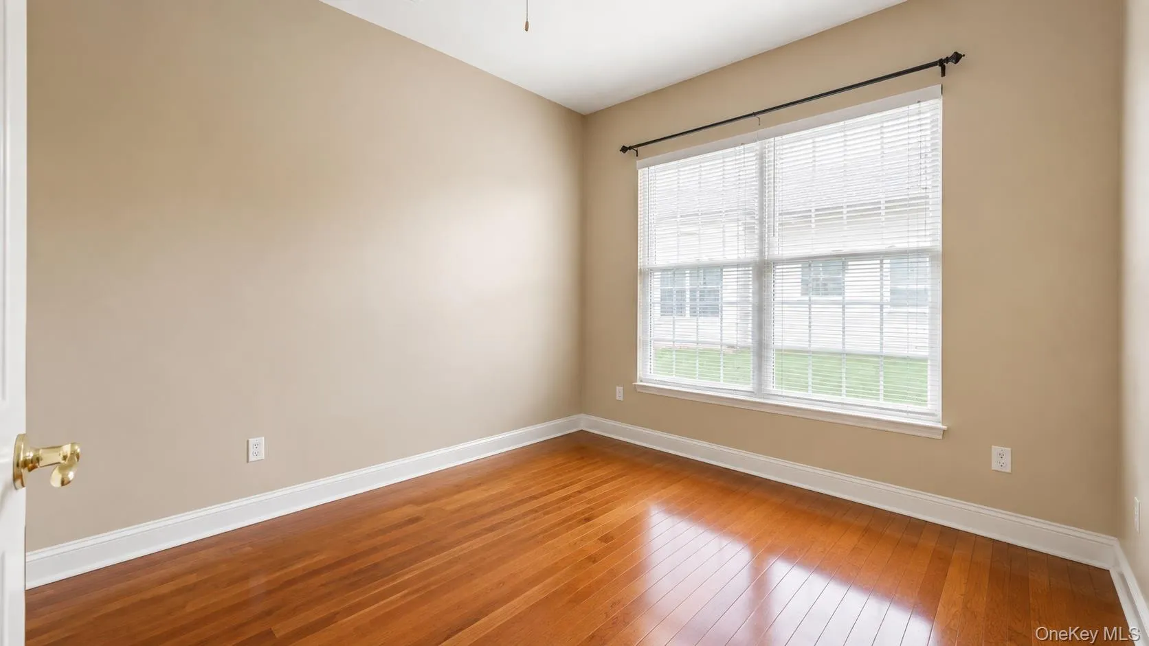 Hardwood flooring, neutral wall tones, white trim, and a window with blinds Hardwood flooring, neutral wall tones, white trim, and a window with blinds