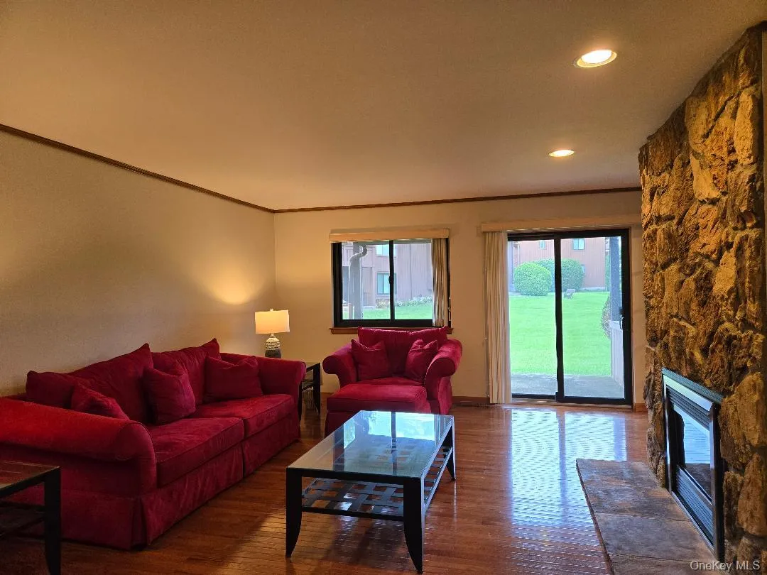 View of the Cavernous Living Room, featuring a beautiful Stone Gas Fplc, recessed lighting, hardwood flooring & sliding glass door to the patio & courtyard.. View of the Cavernous Living Room, featuring a beautiful Stone Gas Fplc, recessed lighting, hardwood flooring & sliding glass door to the patio & courtyard..