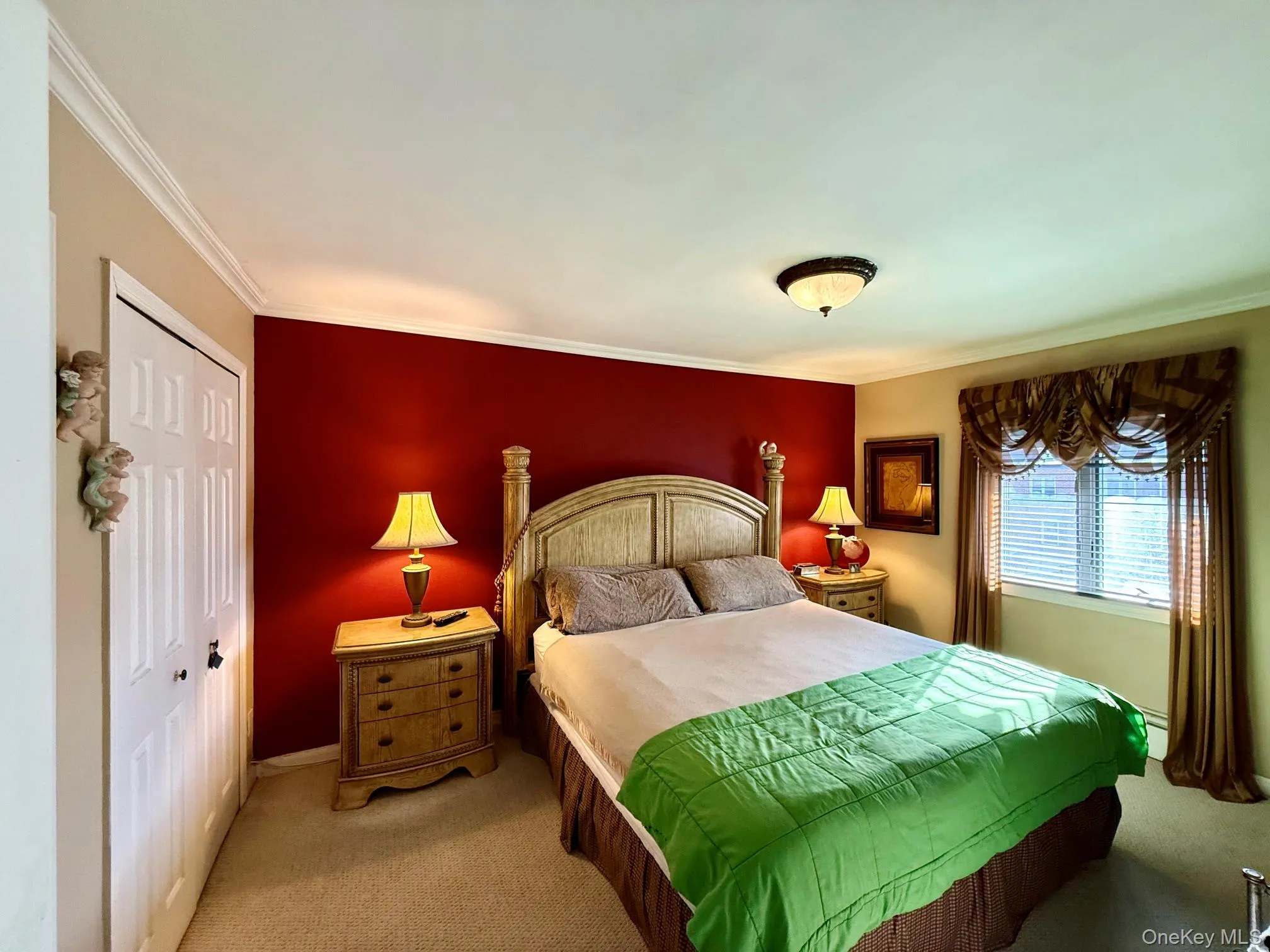 Carpeted bedroom featuring a window with blinds and valance, crown molding, a built-in closet with bi-fold doors, and a ceiling-mounted light fixture Carpeted bedroom featuring a window with blinds and valance, crown molding, a built-in closet with bi-fold doors, and a ceiling-mounted light fixture