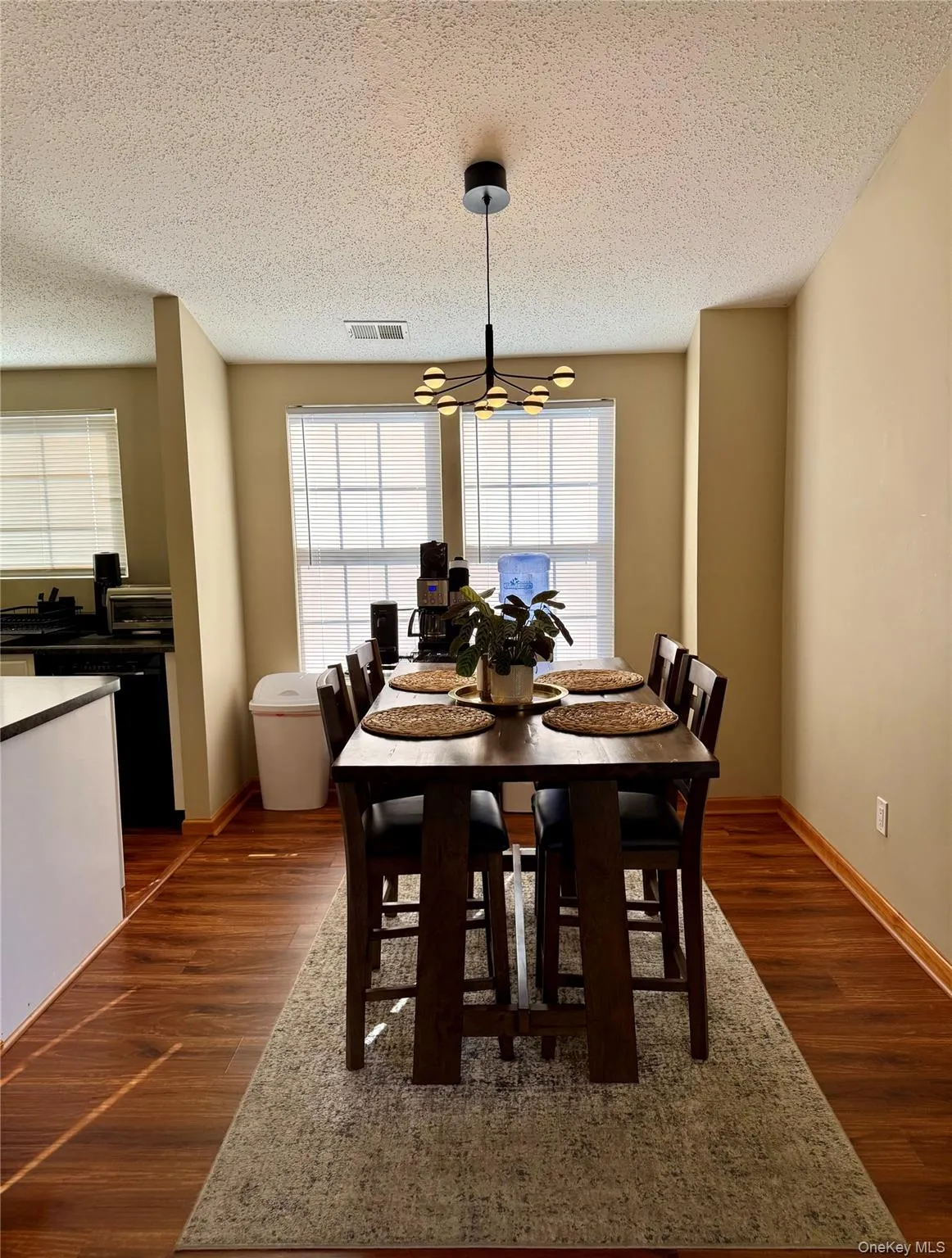 Dining area featuring healthy amount of natural light, a textured ceiling, and dark wood-style flooring Dining area featuring healthy amount of natural light, a textured ceiling, and dark wood-style flooring