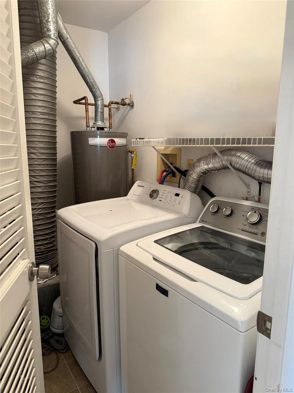 Laundry room with tile patterned flooring, washer and dryer, and gas water heater Laundry room with tile patterned flooring, washer and dryer, and gas water heater
