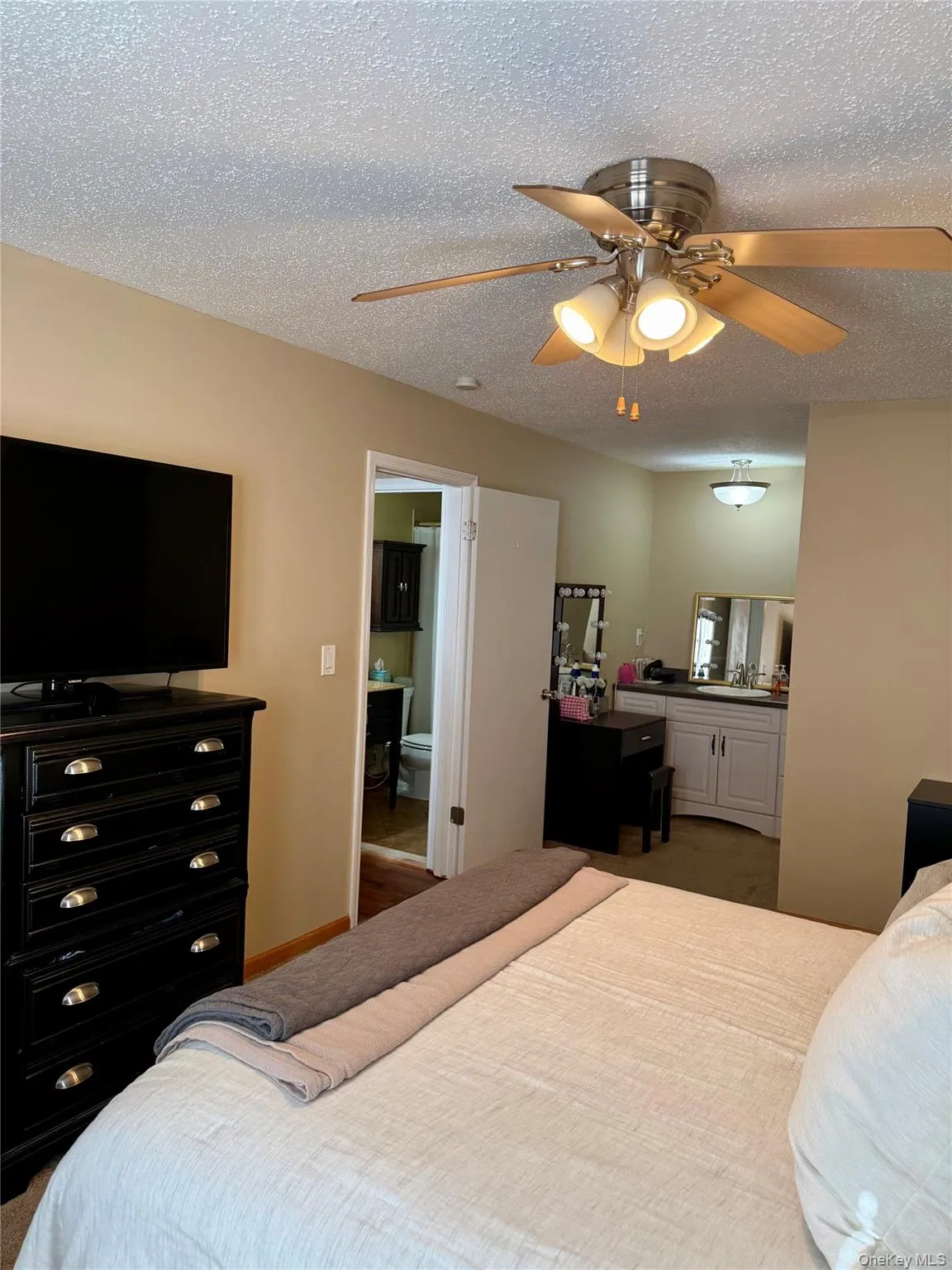 Bedroom with a textured ceiling, a ceiling fan, and carpet flooring Bedroom with a textured ceiling, a ceiling fan, and carpet flooring