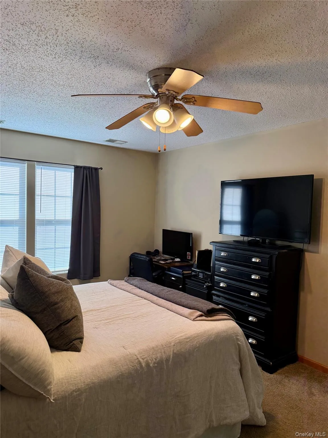Bedroom featuring a textured ceiling, carpet floors, and a ceiling fan Bedroom featuring a textured ceiling, carpet floors, and a ceiling fan