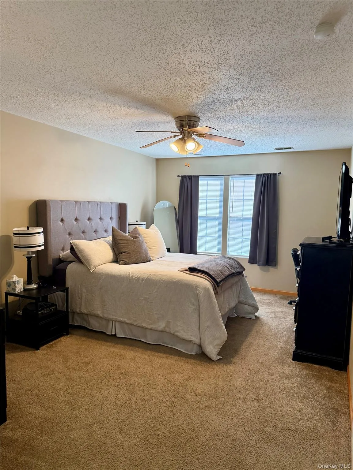 Carpeted bedroom featuring a textured ceiling and ceiling fan Carpeted bedroom featuring a textured ceiling and ceiling fan