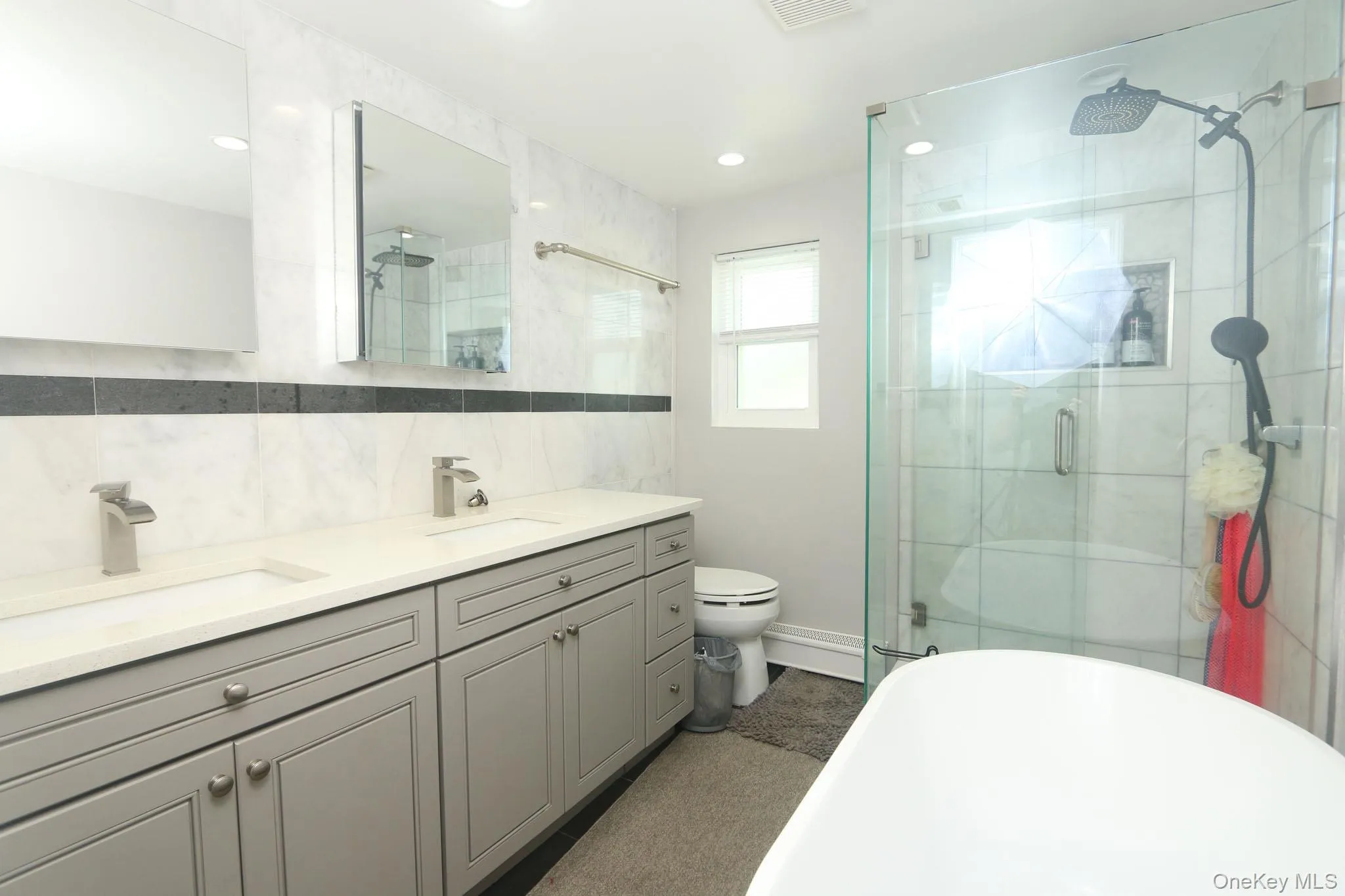 Modern bathroom featuring a double vanity with gray cabinetry, brushed nickel hardware, and a white countertop Modern bathroom featuring a double vanity with gray cabinetry, brushed nickel hardware, and a white countertop