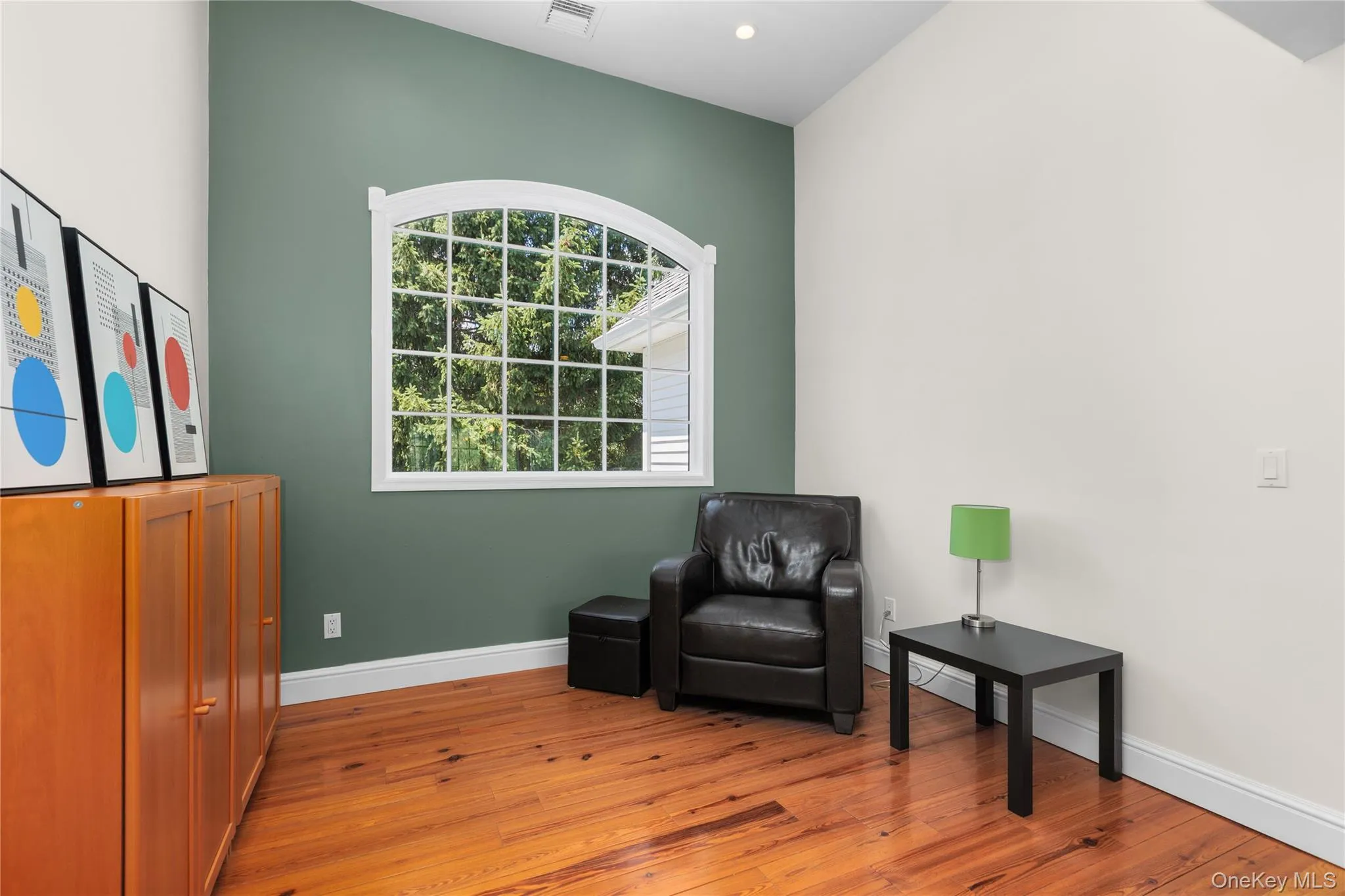 Vaulted ceiling, arched window with grid pattern, hardwood flooring, two-tone painted walls, and recessed lighting Vaulted ceiling, arched window with grid pattern, hardwood flooring, two-tone painted walls, and recessed lighting