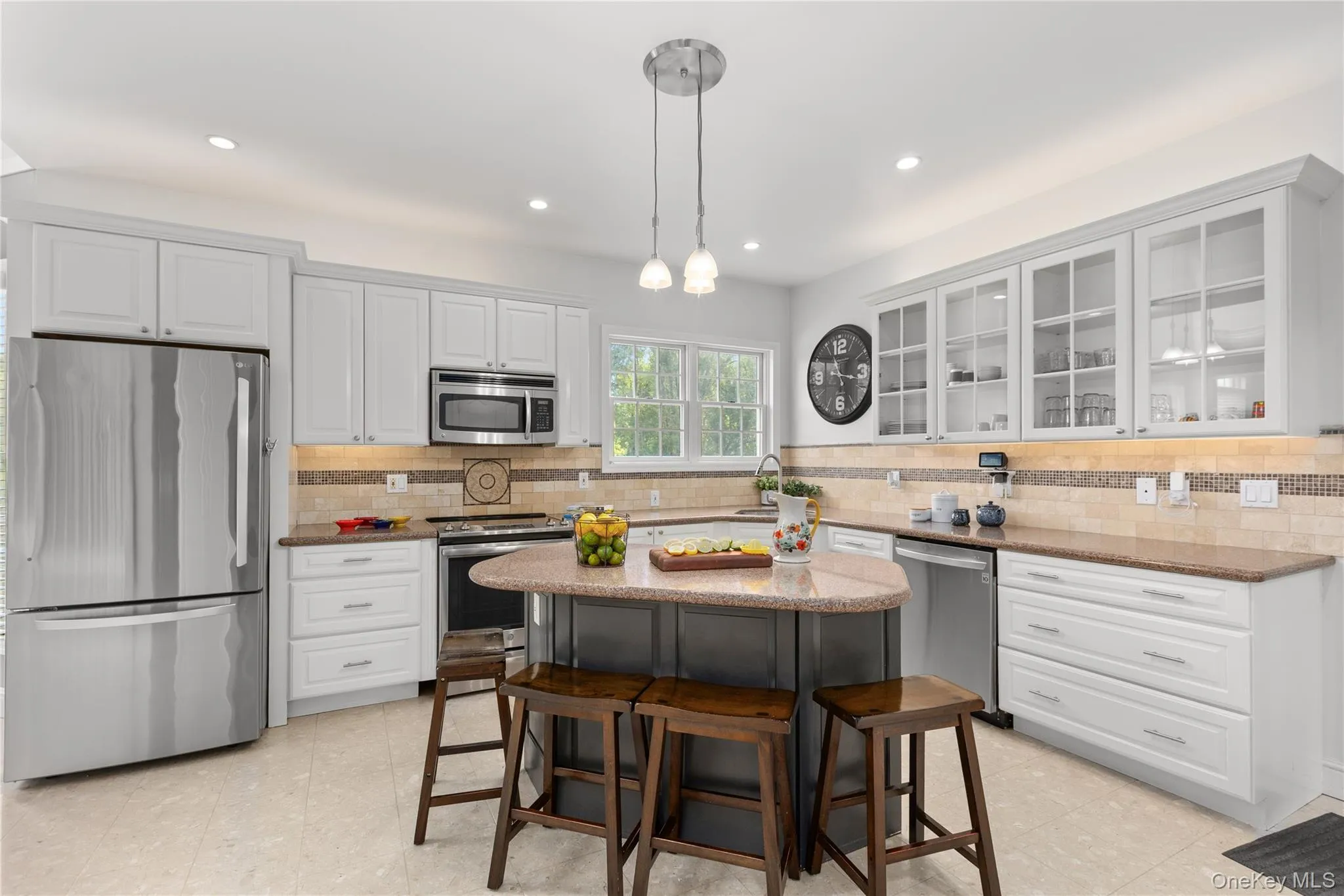 Chefs' kitchen featuring white shaker cabinetry with glass-front uppers, stainless refrigerator, oven/range, microwave, dishwasher. Chefs' kitchen featuring white shaker cabinetry with glass-front uppers, stainless refrigerator, oven/range, microwave, dishwasher.