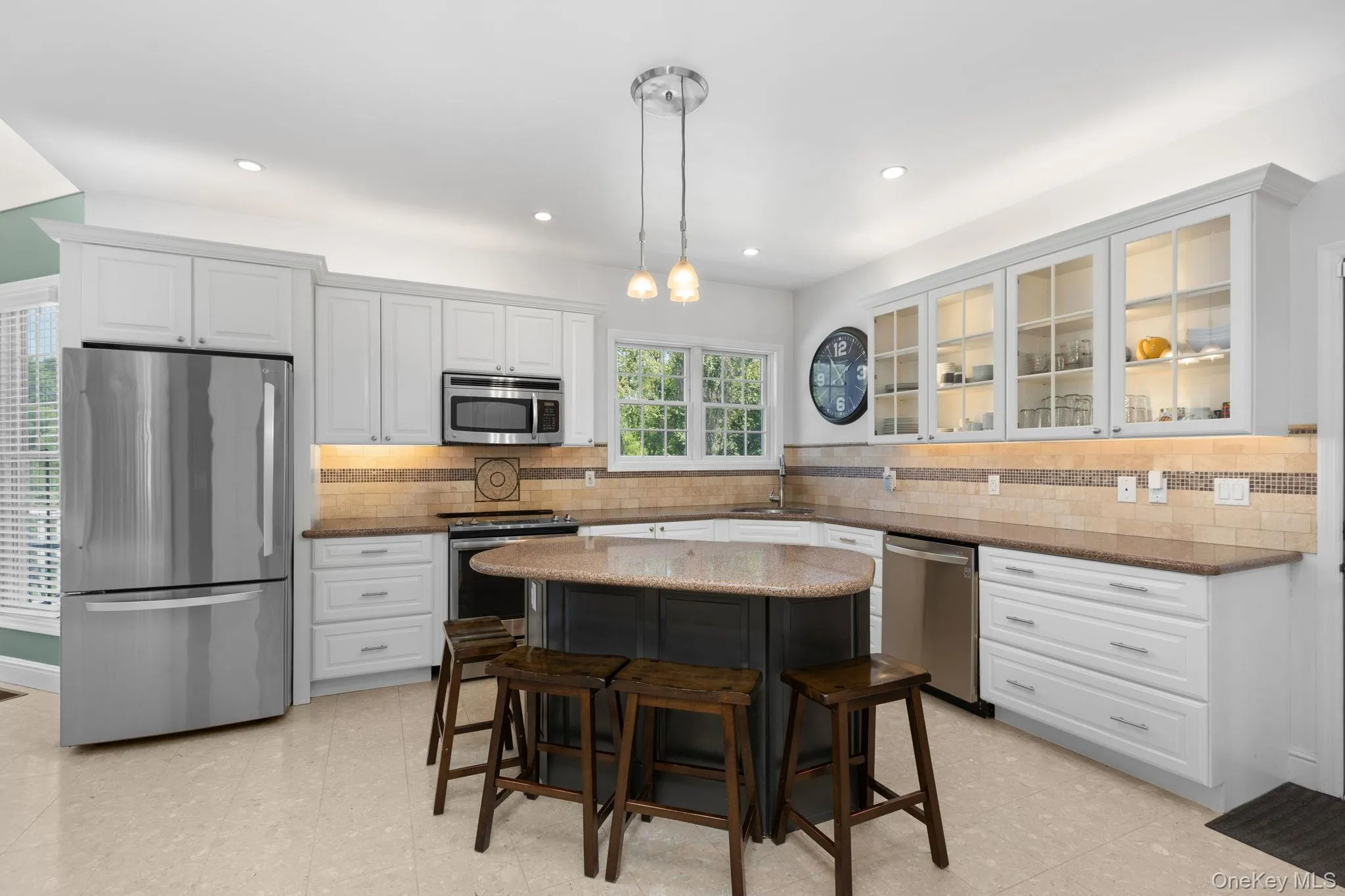 Chefs' kitchen featuring white shaker cabinetry with glass-front uppers, stainless refrigerator, oven/range, microwave, dishwasher. Chefs' kitchen featuring white shaker cabinetry with glass-front uppers, stainless refrigerator, oven/range, microwave, dishwasher.