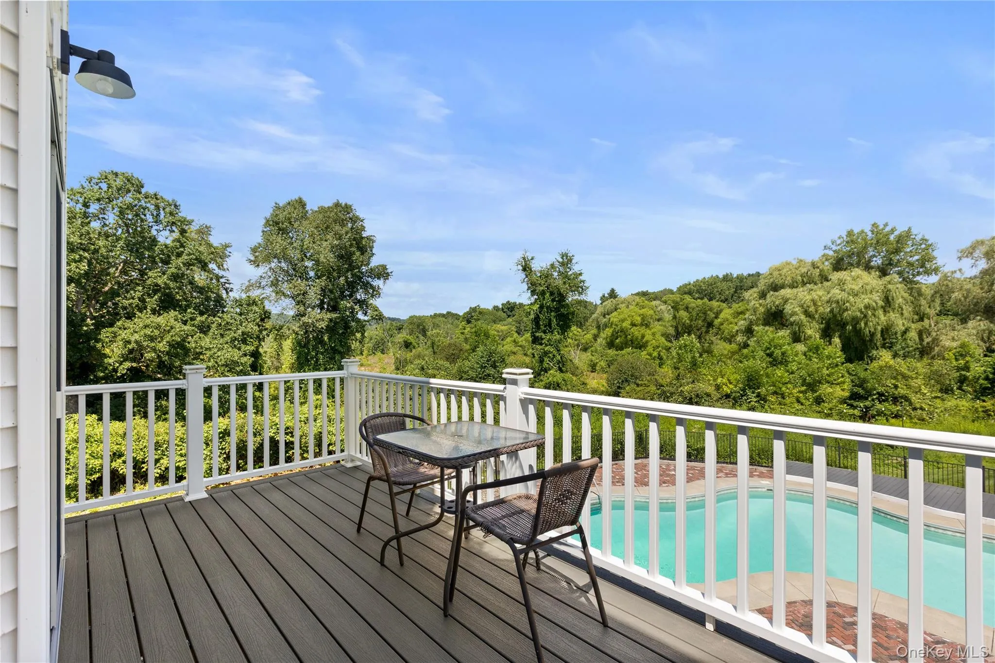 Spacious outdoor deck overlooking pool and tree lined property Spacious outdoor deck overlooking pool and tree lined property