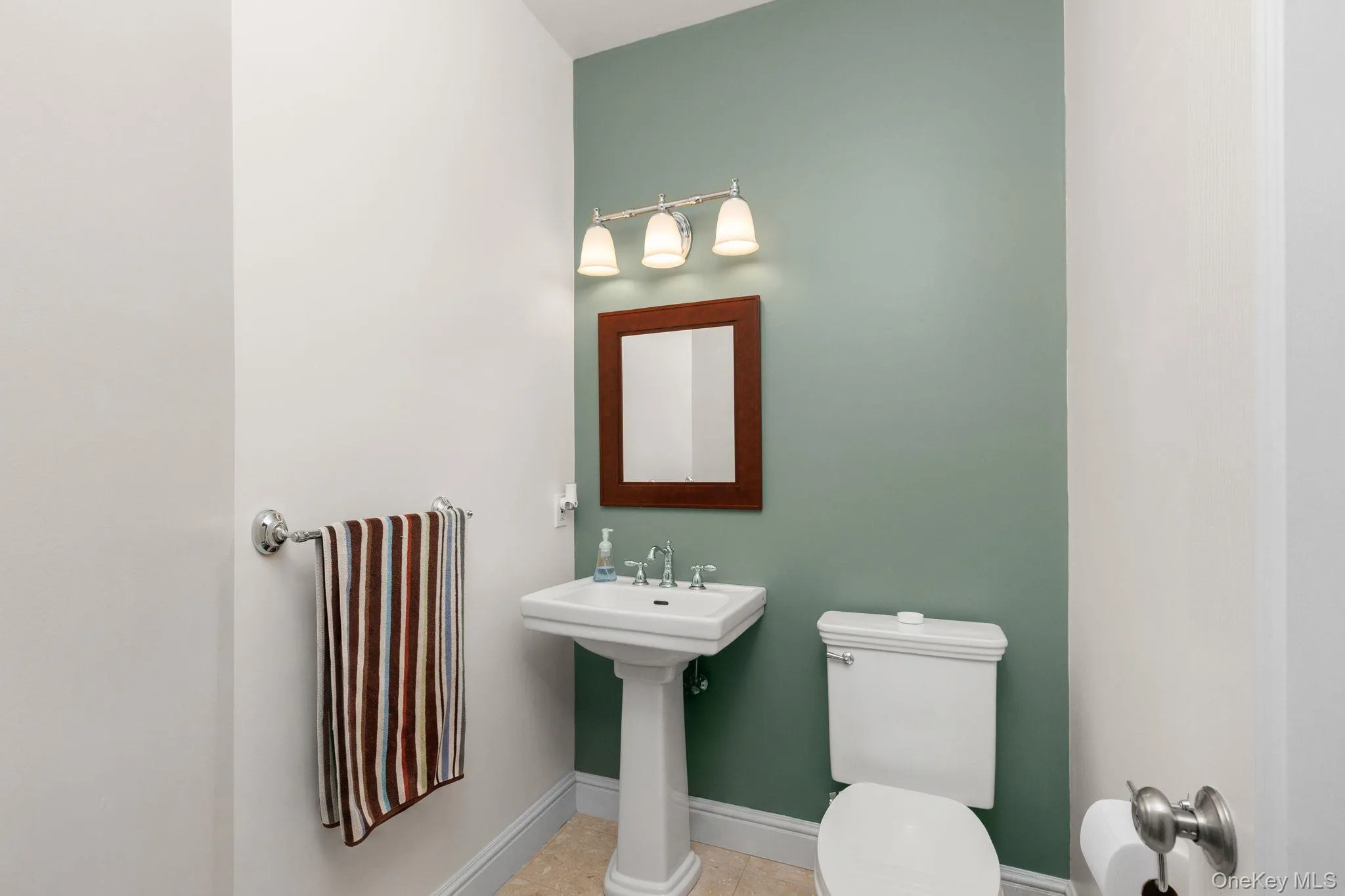 Half bathroom pedestal sink, mounted mirror, wall-mounted light fixture, and toilet Half bathroom pedestal sink, mounted mirror, wall-mounted light fixture, and toilet