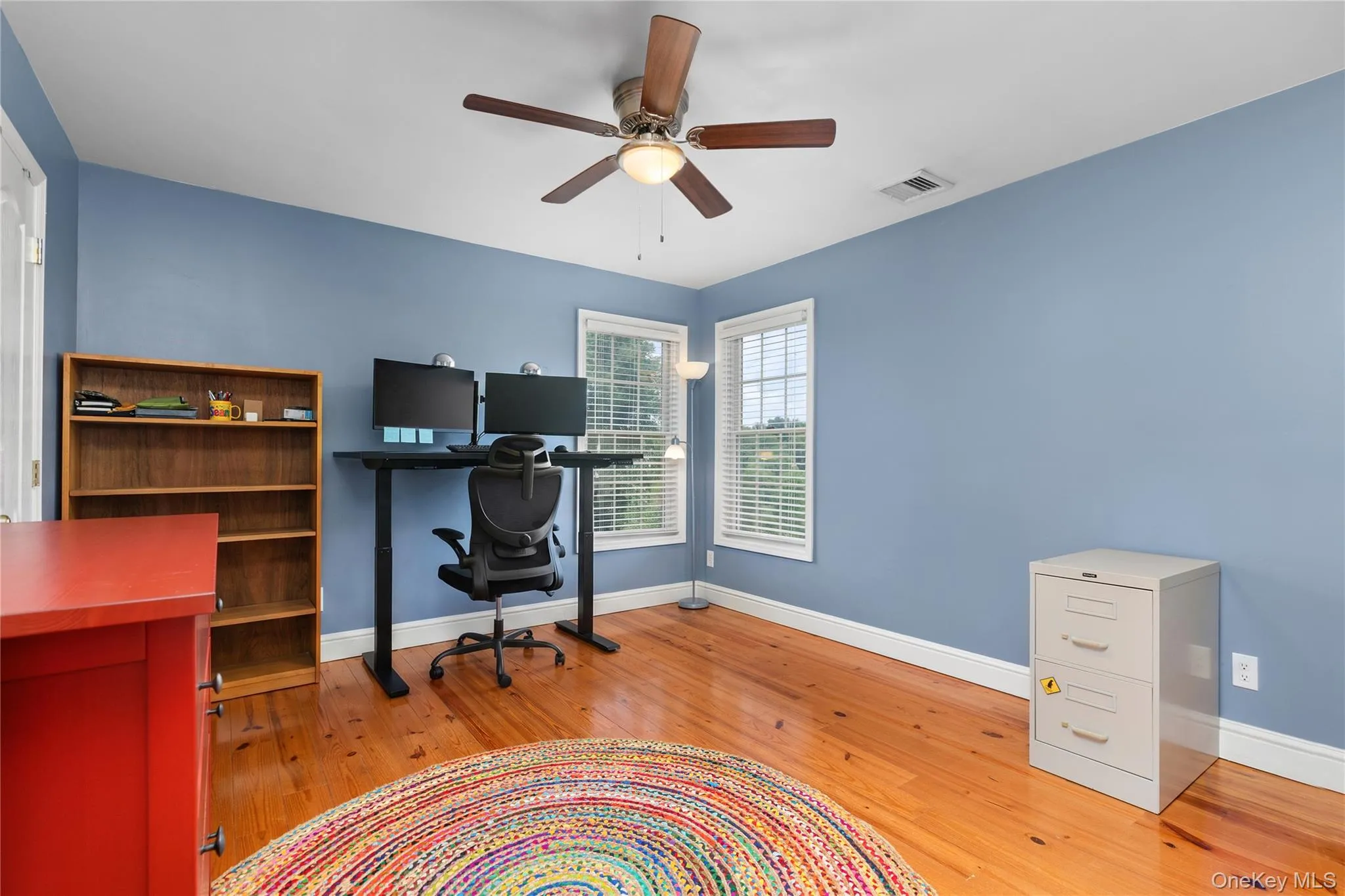 Spacious room with hard wood flooring, two windows with blinds, a ceiling fan with integrated lighting, Spacious room with hard wood flooring, two windows with blinds, a ceiling fan with integrated lighting,