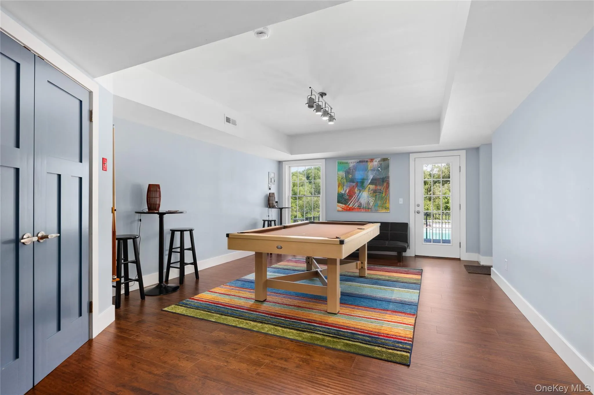 Spacious recreation area featuring hardwood flooring, light blue walls, and white trim Spacious recreation area featuring hardwood flooring, light blue walls, and white trim