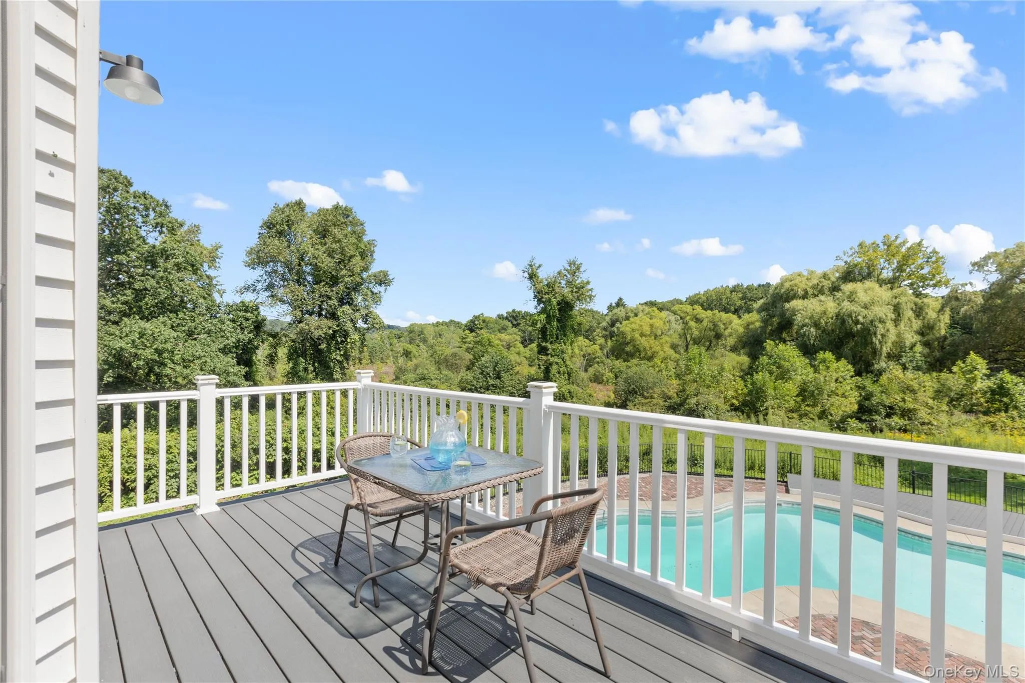 Spacious outdoor deck overlooking pool and tree lined property Spacious outdoor deck overlooking pool and tree lined property