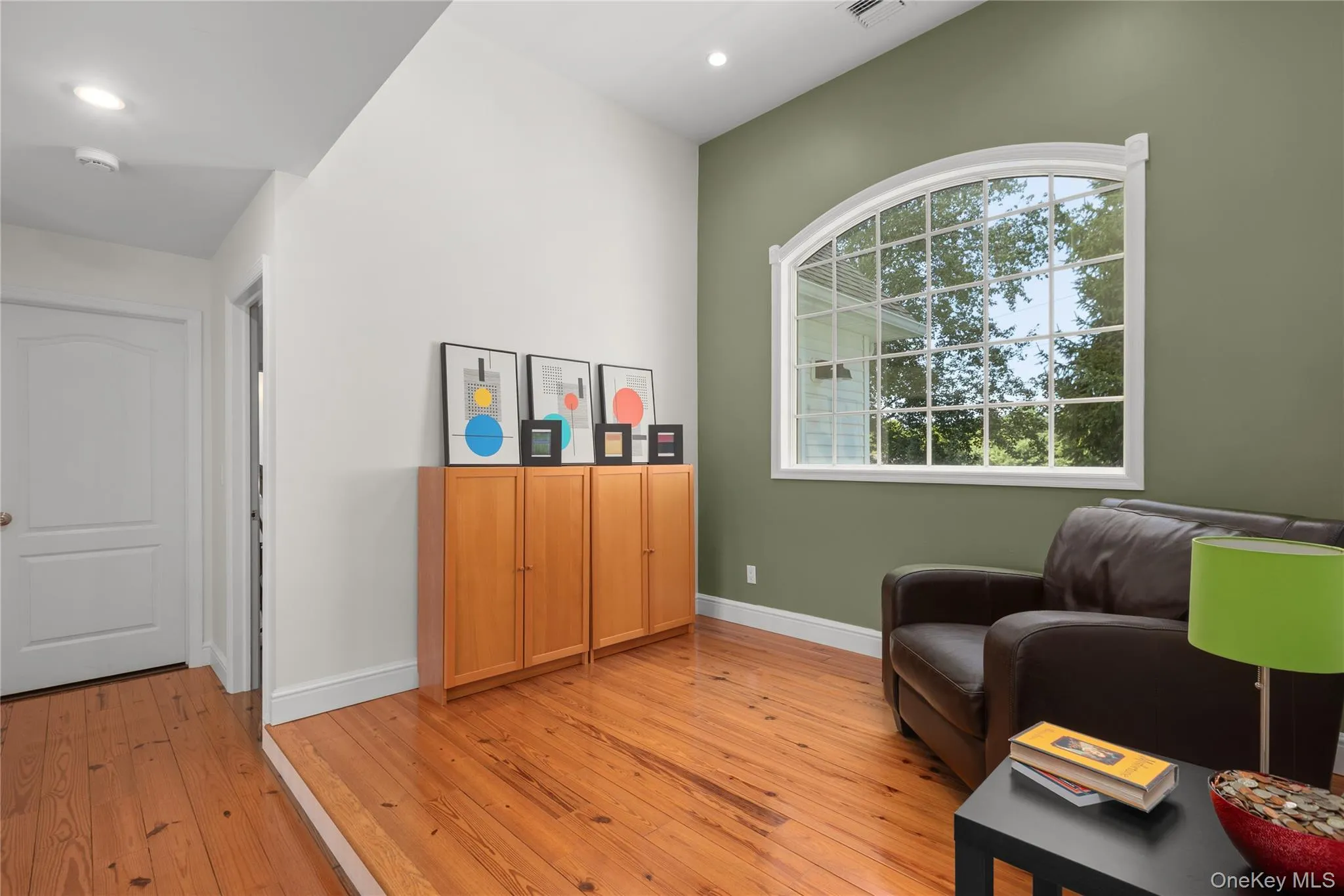 Vaulted ceiling, arched window with grid pattern, hardwood flooring, two-tone painted walls, and recessed lighting Vaulted ceiling, arched window with grid pattern, hardwood flooring, two-tone painted walls, and recessed lighting