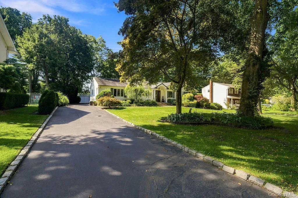 Paved driveway with stone border, expansive lawn, and mature trees Paved driveway with stone border, expansive lawn, and mature trees
