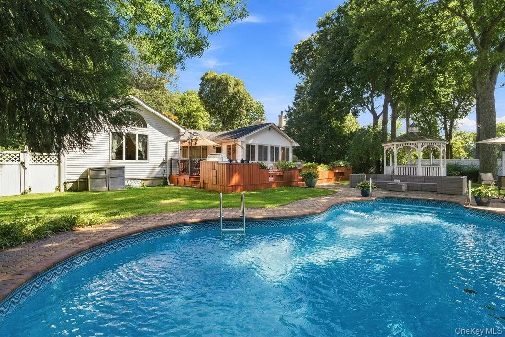 Resort-style backyard featuring a kidney-shaped pool with brick coping, a multi-level wood deck, a white gazebo, and a manicured lawn Resort-style backyard featuring a kidney-shaped pool with brick coping, a multi-level wood deck, a white gazebo, and a manicured lawn
