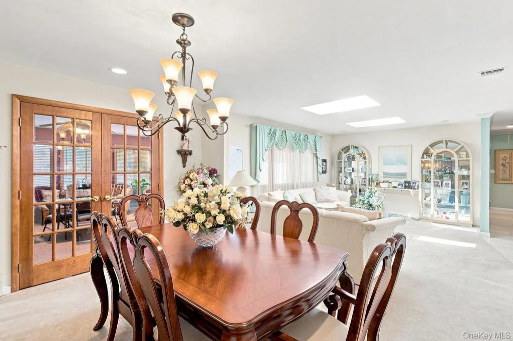Wood-finish French doors, central chandelier, recessed lighting, and dual skylights Wood-finish French doors, central chandelier, recessed lighting, and dual skylights