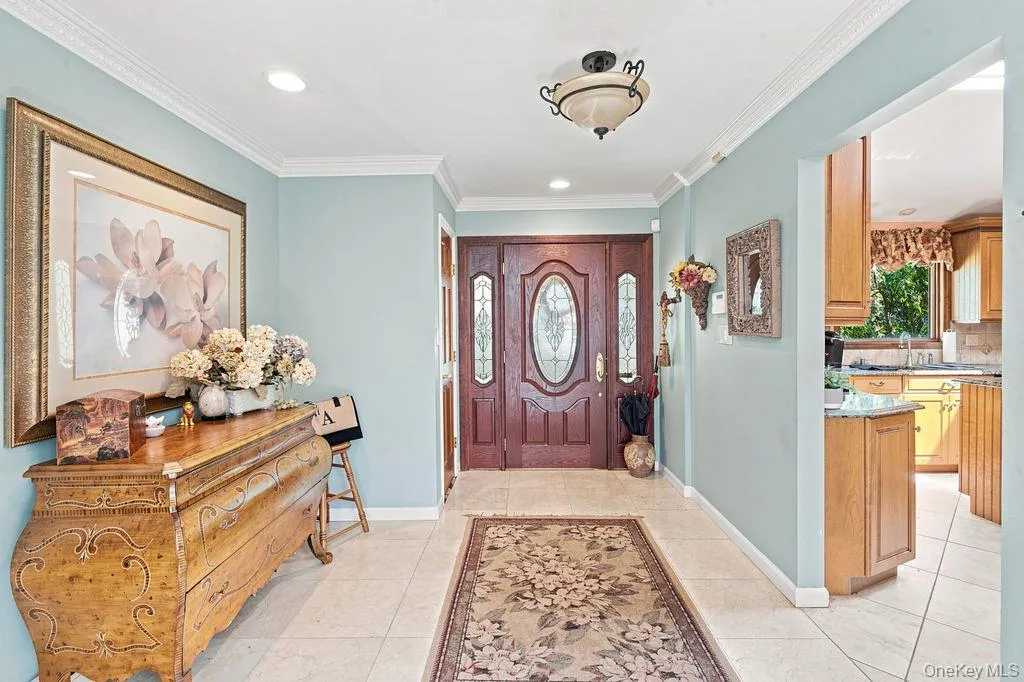 Entryway featuring a wood-panel door with decorative glass inserts, crown molding, recessed lighting, and tile flooring Entryway featuring a wood-panel door with decorative glass inserts, crown molding, recessed lighting, and tile flooring