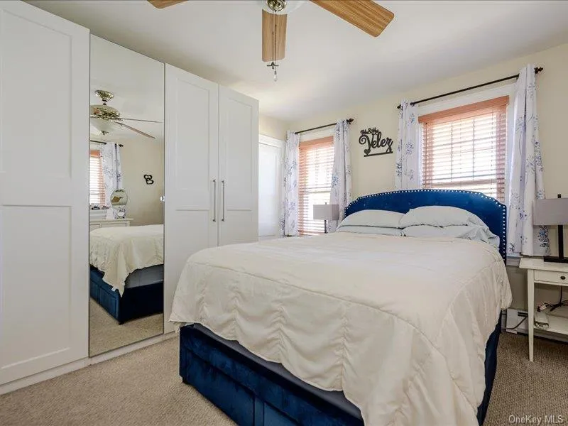 Master Bedroom featuring light beige carpeting, two windows with wood blinds, and a ceiling fan with wood-finish blades Master Bedroom featuring light beige carpeting, two windows with wood blinds, and a ceiling fan with wood-finish blades