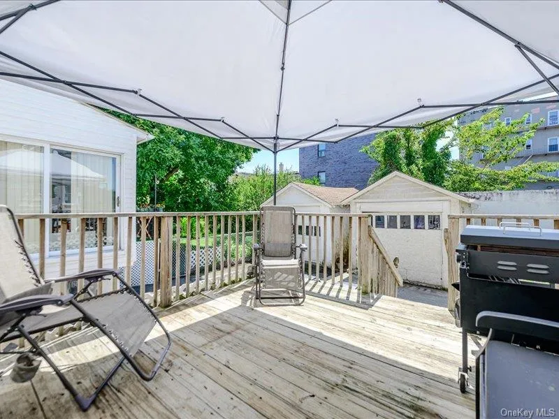 Expansive wood-finish deck with a wood railing and a white tent for shade Expansive wood-finish deck with a wood railing and a white tent for shade