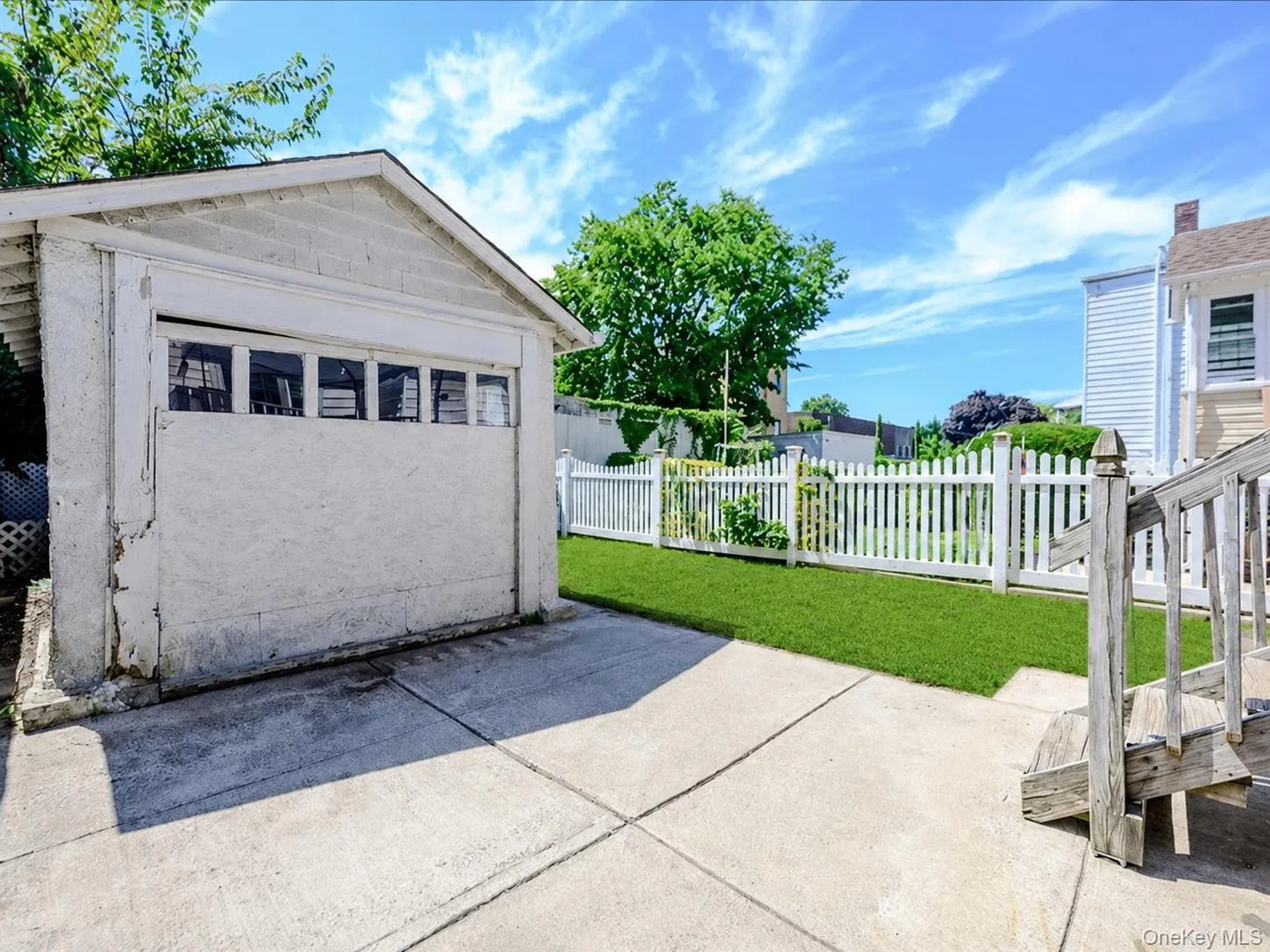Detached garage with upper window panels, concrete driveway, and a fenced grassy yard. ai generated Detached garage with upper window panels, concrete driveway, and a fenced grassy yard. ai generated