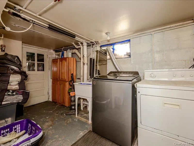 Laundry area featuring a utility sink, exposed piping, and a glass-paneled door Laundry area featuring a utility sink, exposed piping, and a glass-paneled door