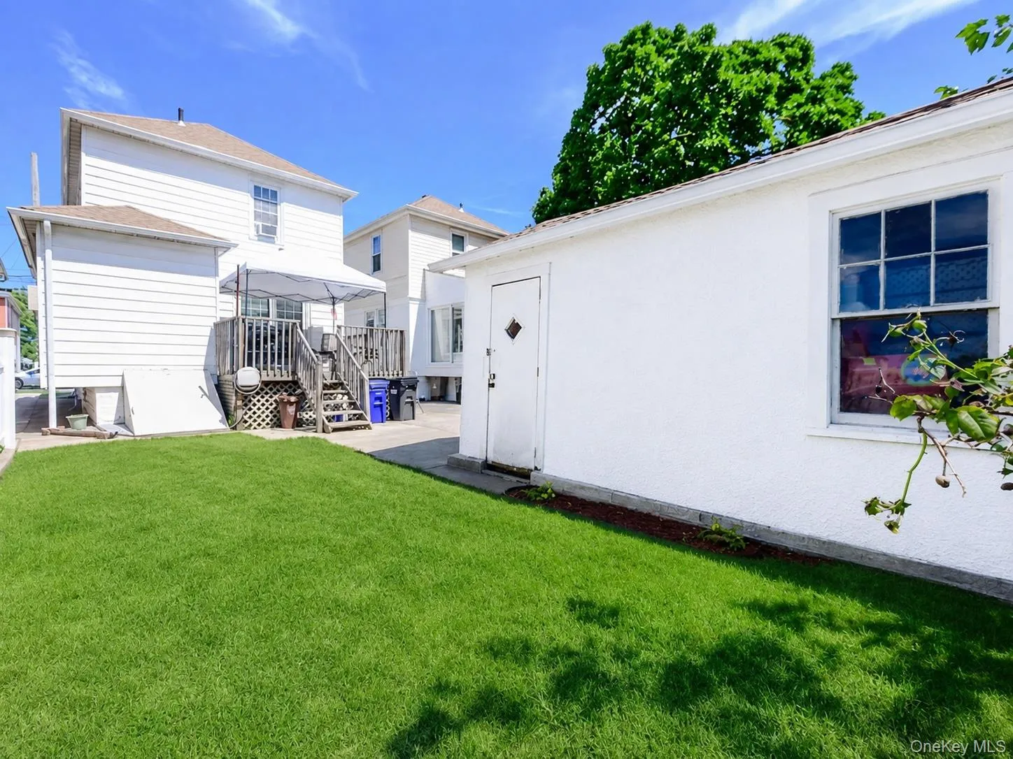 Private backyard featuring a well-maintained lawn, a wooden deck, and a stucco-finished outbuilding with a single window. ai generated Private backyard featuring a well-maintained lawn, a wooden deck, and a stucco-finished outbuilding with a single window. ai generated