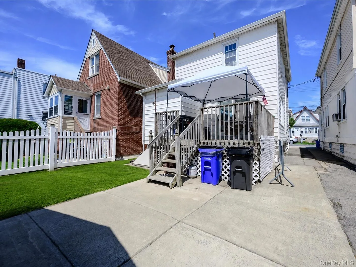 Rear yard featuring a wood deck with stairs, white picket fence, and a grass lawn. ai generated. Rear yard featuring a wood deck with stairs, white picket fence, and a grass lawn. ai generated.