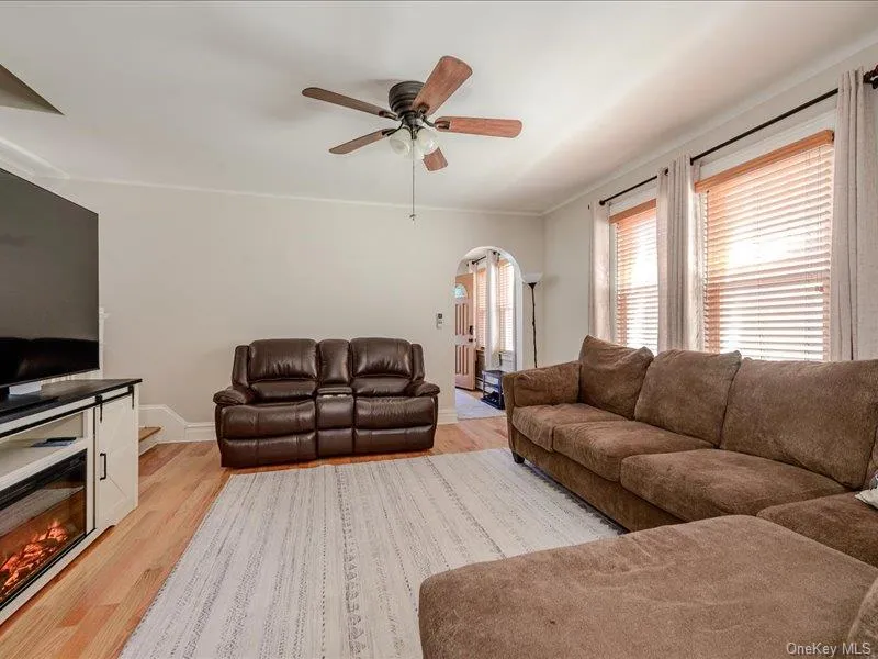 Living area featuring wood-finish flooring, a ceiling fan with light fixture, and archway entry Living area featuring wood-finish flooring, a ceiling fan with light fixture, and archway entry