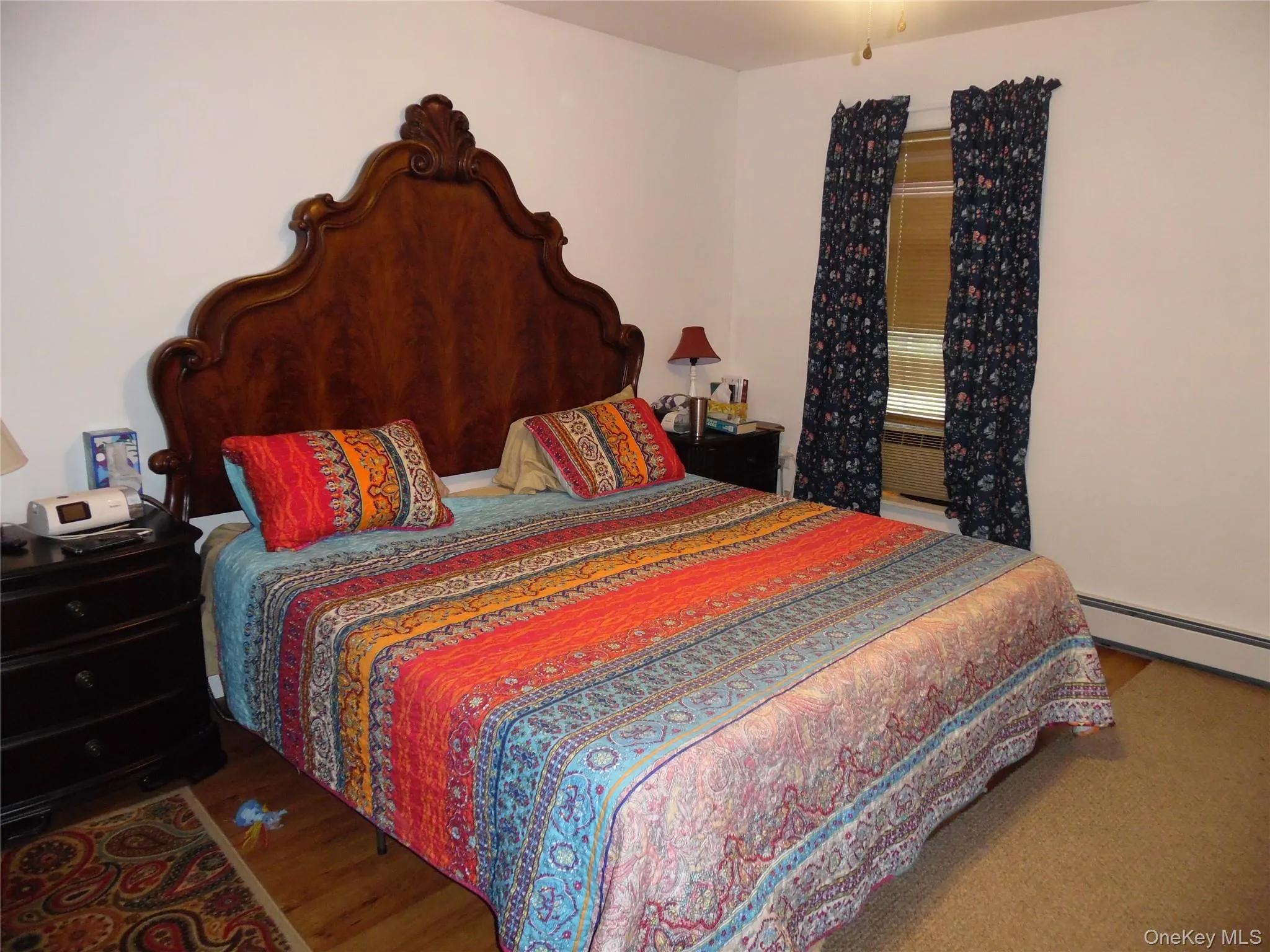 Spacious master bedroom room featuring a decorative wood headboard, hardwood flooring, and neutral wall tones Spacious master bedroom room featuring a decorative wood headboard, hardwood flooring, and neutral wall tones