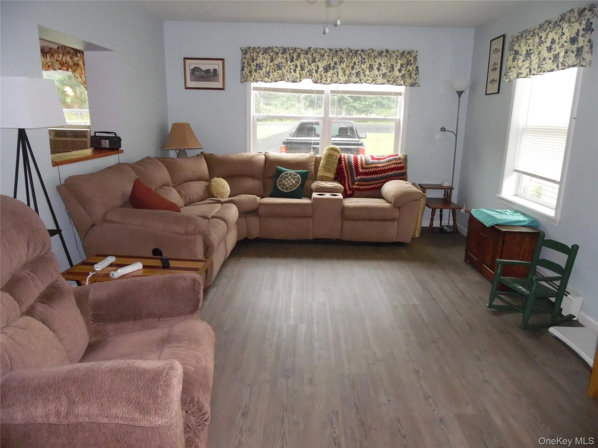 Spacious living room featuring light blue walls and wood-finish flooring Spacious living room featuring light blue walls and wood-finish flooring