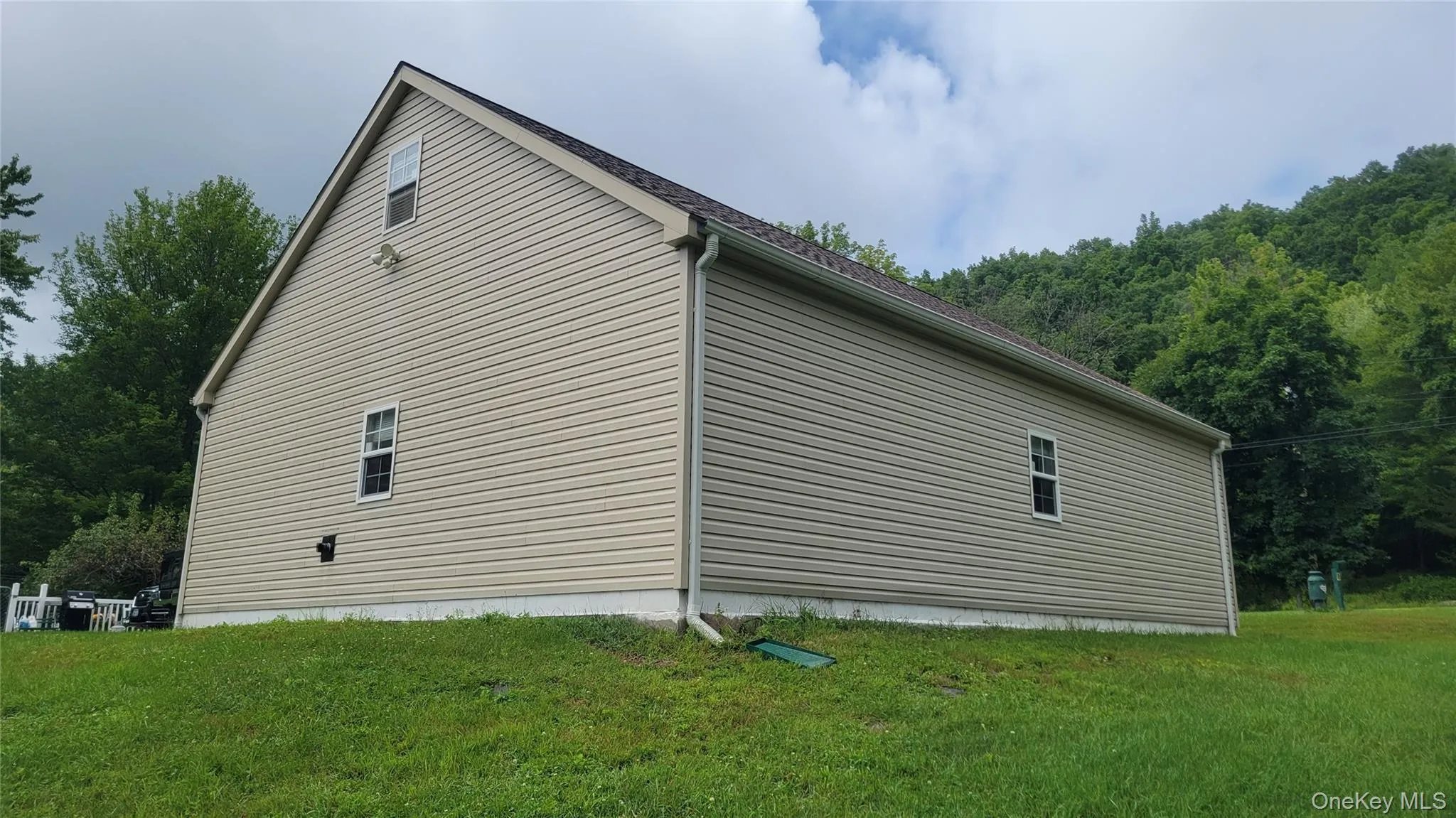 Exterior of garage featuring beige vinyl siding, white trim windows, a brown shingle roof, and a visible gutter system Exterior of garage featuring beige vinyl siding, white trim windows, a brown shingle roof, and a visible gutter system