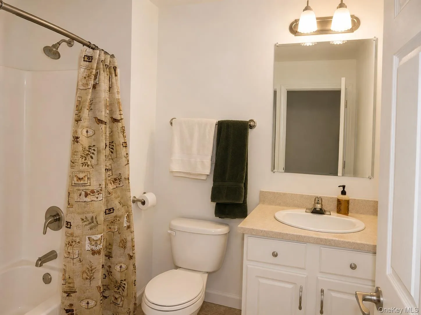 Bathroom featuring a white bathtub, toilet, and vanity with an integrated sink Bathroom featuring a white bathtub, toilet, and vanity with an integrated sink