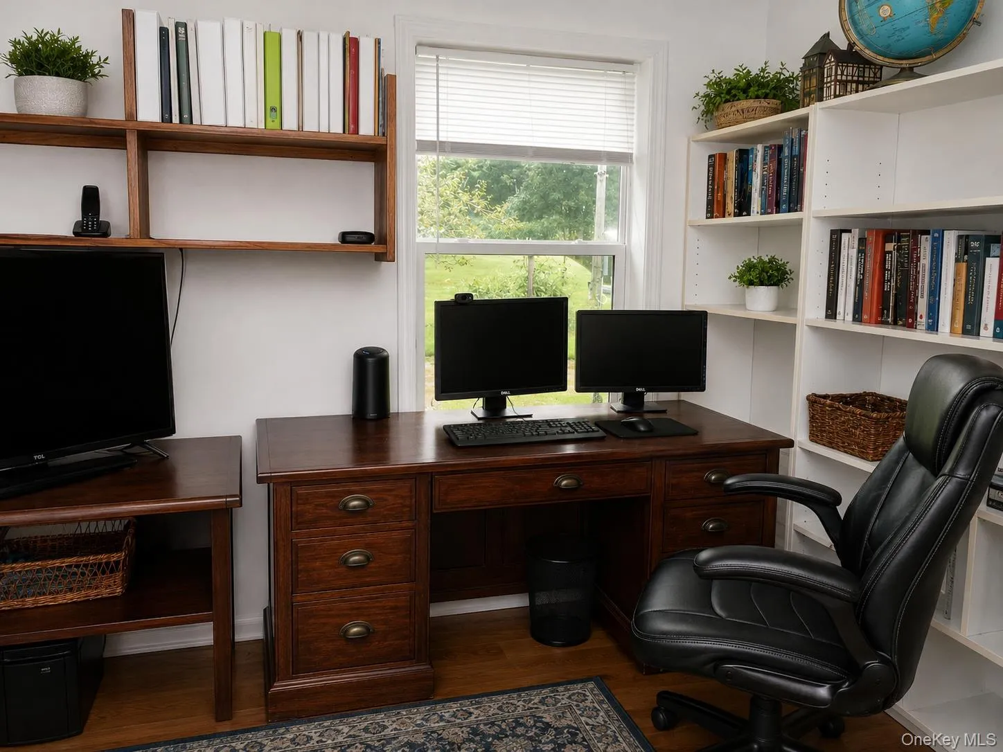 Dedicated office space featuring hardwood flooring, white shelving, a window with blinds, and built-in wood-finish shelving Dedicated office space featuring hardwood flooring, white shelving, a window with blinds, and built-in wood-finish shelving