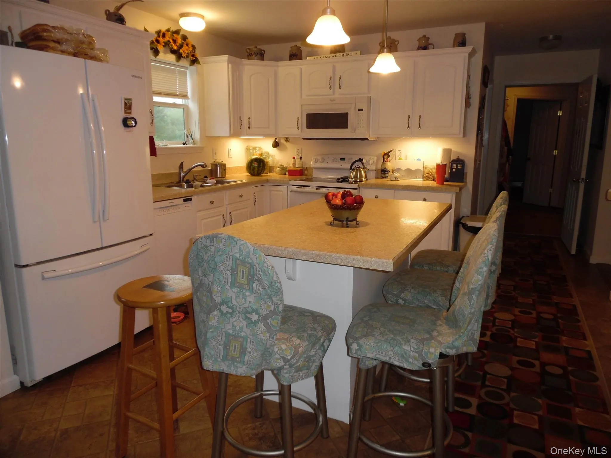 Kitchen featuring a central island with countertop, white cabinetry with hardware, a built-in microwave, and pendant lighting Kitchen featuring a central island with countertop, white cabinetry with hardware, a built-in microwave, and pendant lighting