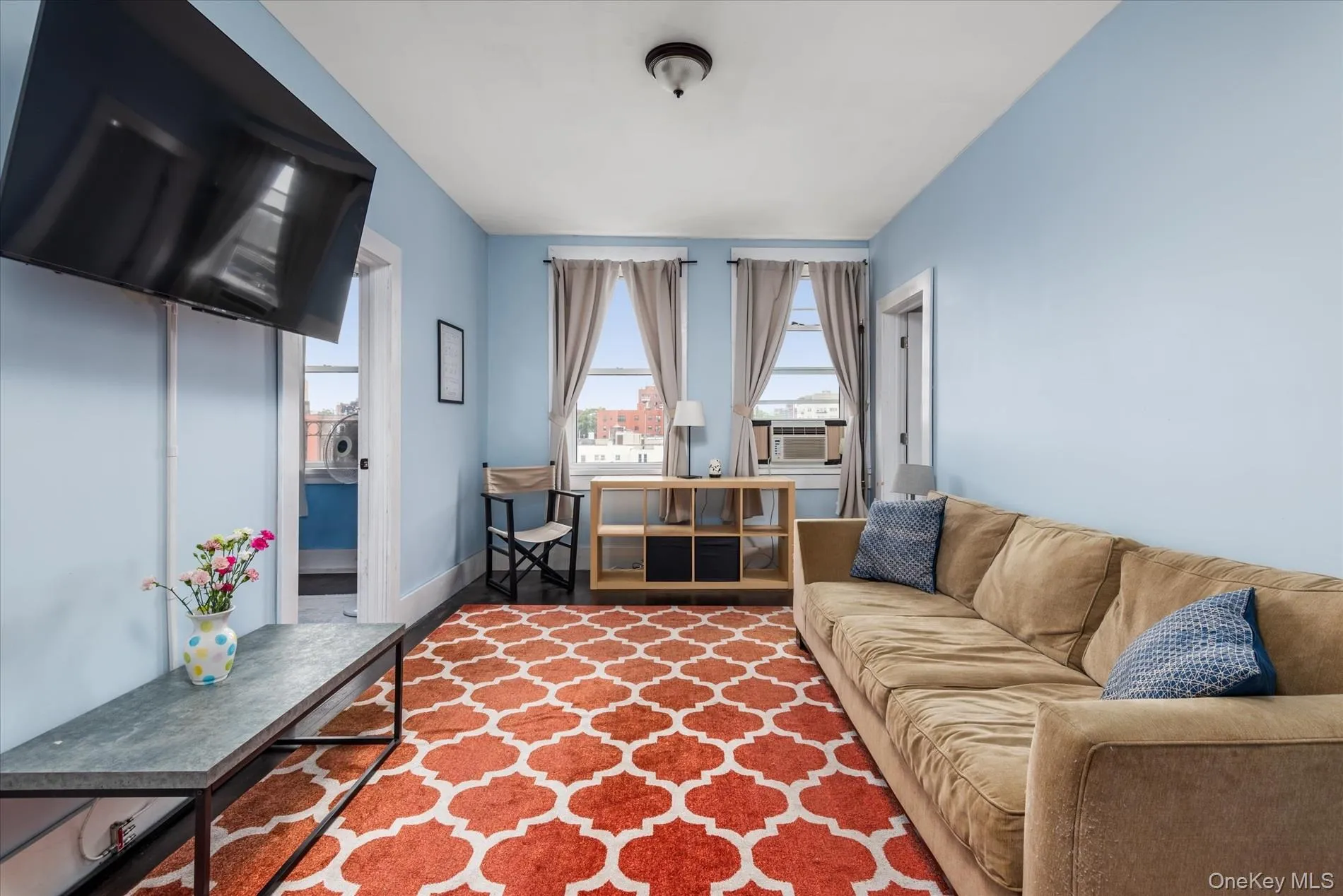 Spacious living area featuring light blue walls, a white ceiling, and dark wood-finish flooring Spacious living area featuring light blue walls, a white ceiling, and dark wood-finish flooring
