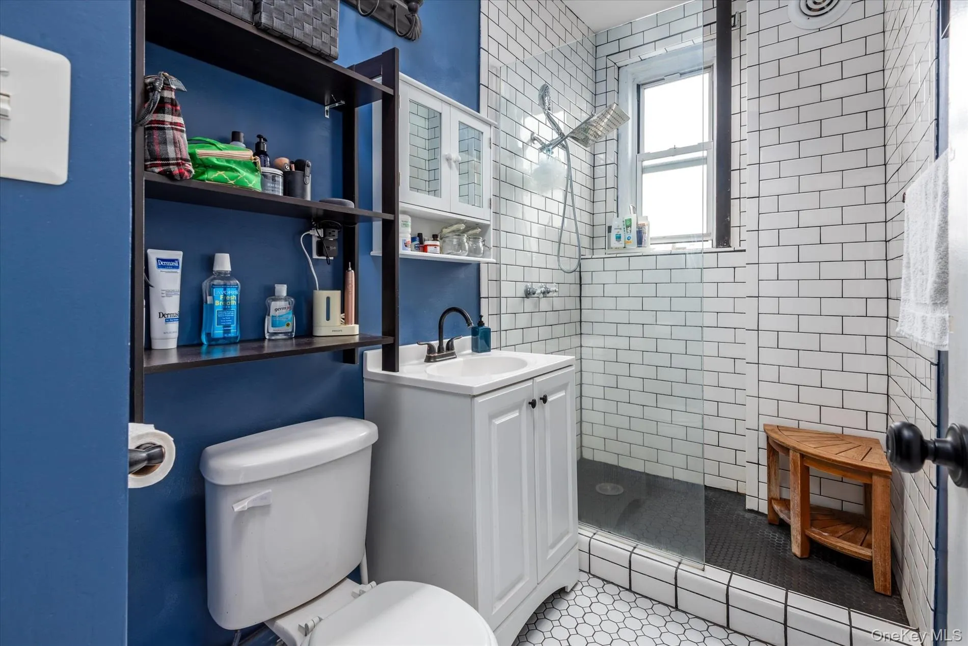 Contemporary bathroom featuring hexagon tile flooring, subway tile shower surround, window-equipped shower, and a vanity with a dark faucet Contemporary bathroom featuring hexagon tile flooring, subway tile shower surround, window-equipped shower, and a vanity with a dark faucet