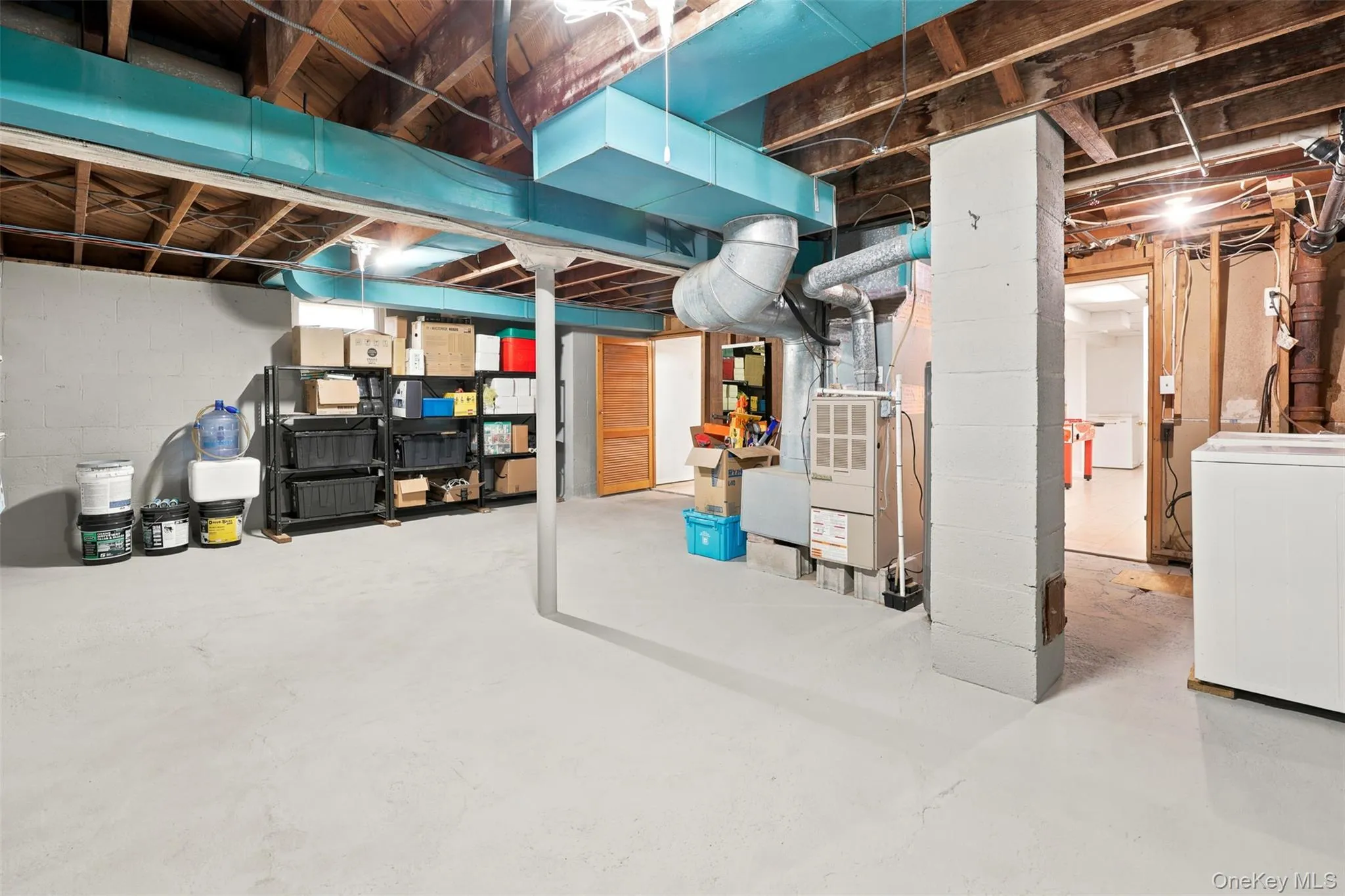 Unfinished basement with painted concrete flooring, exposed ceiling joists, and visible utility infrastructure Unfinished basement with painted concrete flooring, exposed ceiling joists, and visible utility infrastructure