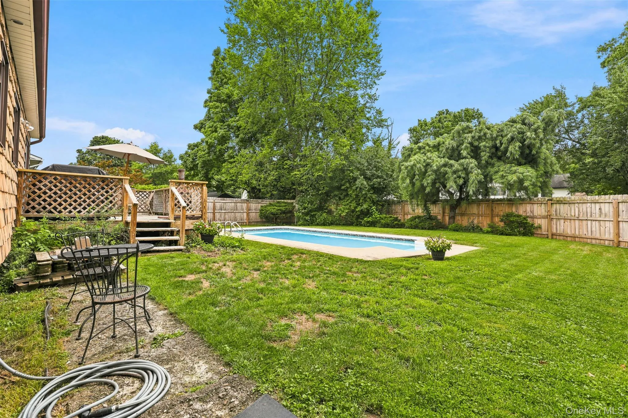 Expansive backyard featuring a fenced perimeter, in-ground swimming pool, and a multi-level wooden deck Expansive backyard featuring a fenced perimeter, in-ground swimming pool, and a multi-level wooden deck