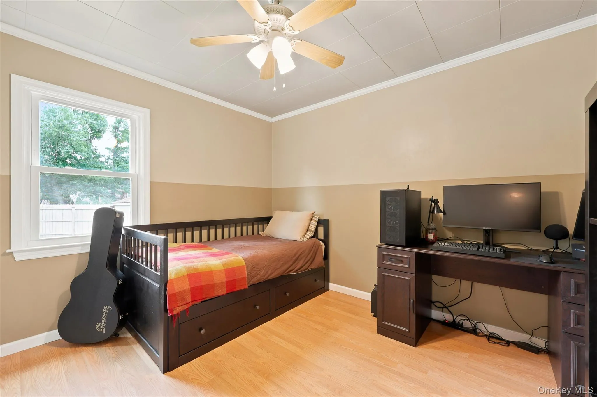 Bedroom featuring wood-finish flooring, a contemporary ceiling fan, and a single window with white trim Bedroom featuring wood-finish flooring, a contemporary ceiling fan, and a single window with white trim