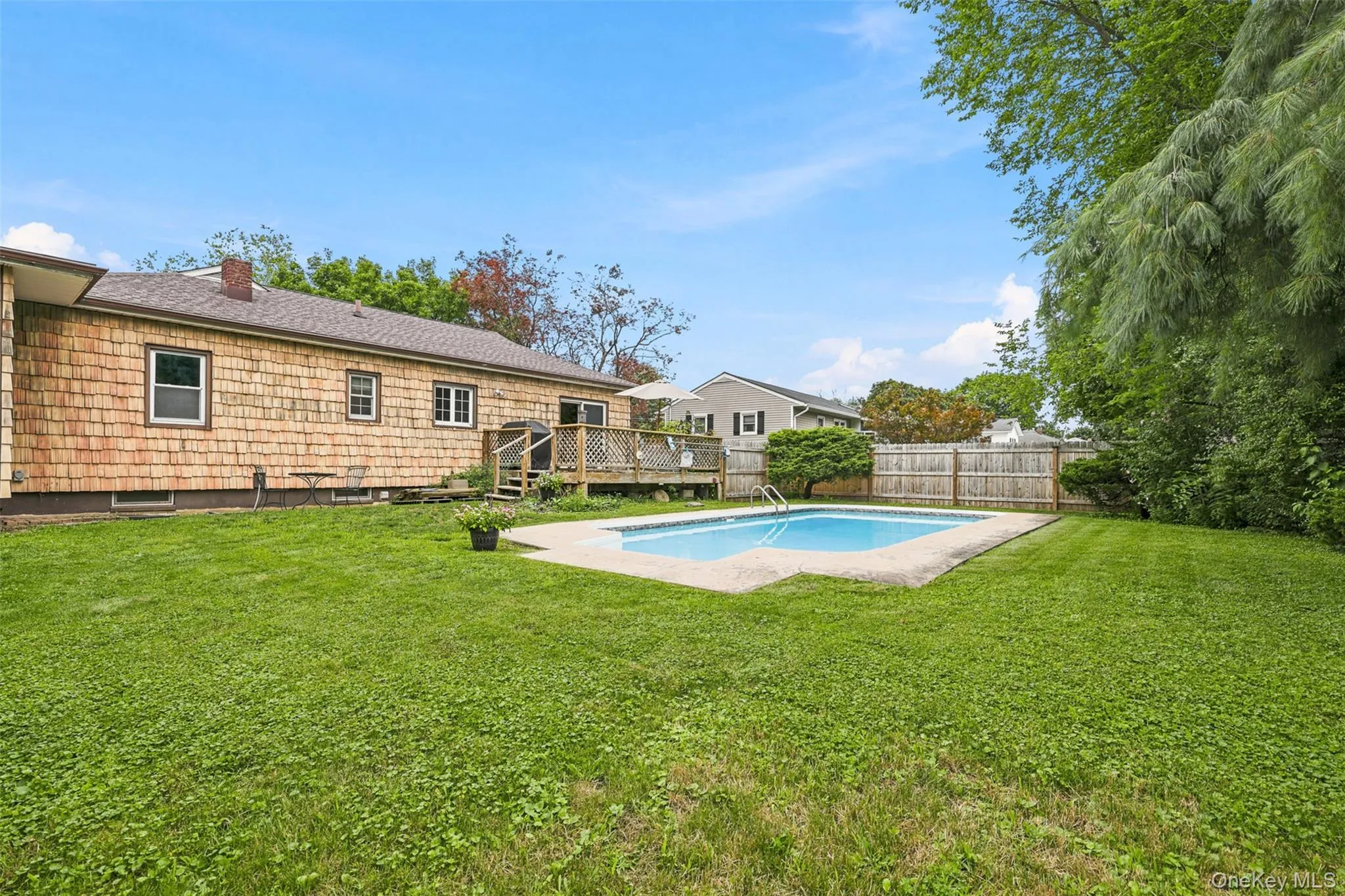 Expansive backyard featuring a fenced perimeter, in-ground swimming pool, and a multi-level wooden deck Expansive backyard featuring a fenced perimeter, in-ground swimming pool, and a multi-level wooden deck
