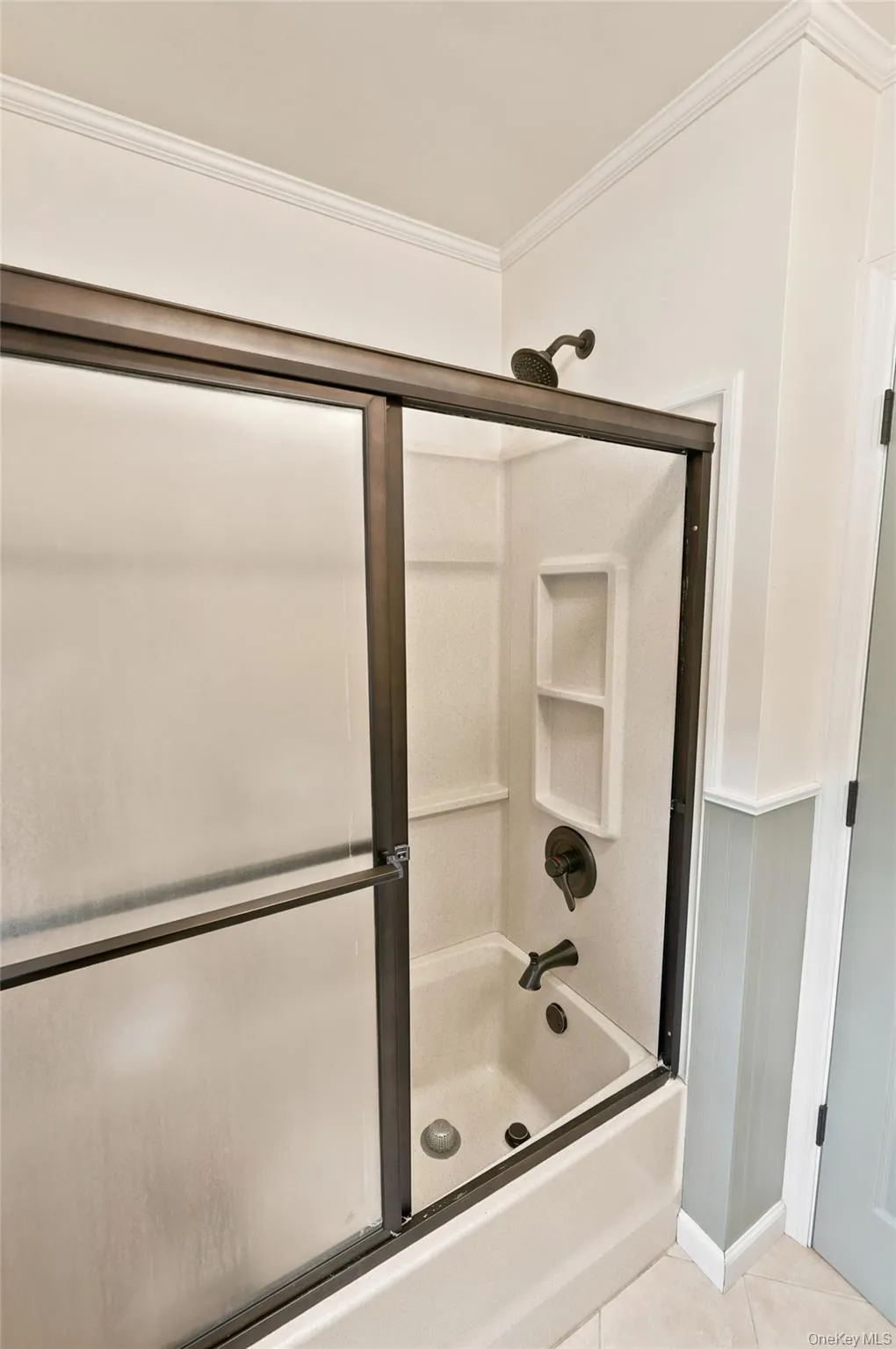 Bathtub and shower combination featuring a bronze-finish sliding glass door enclosure Bathtub and shower combination featuring a bronze-finish sliding glass door enclosure