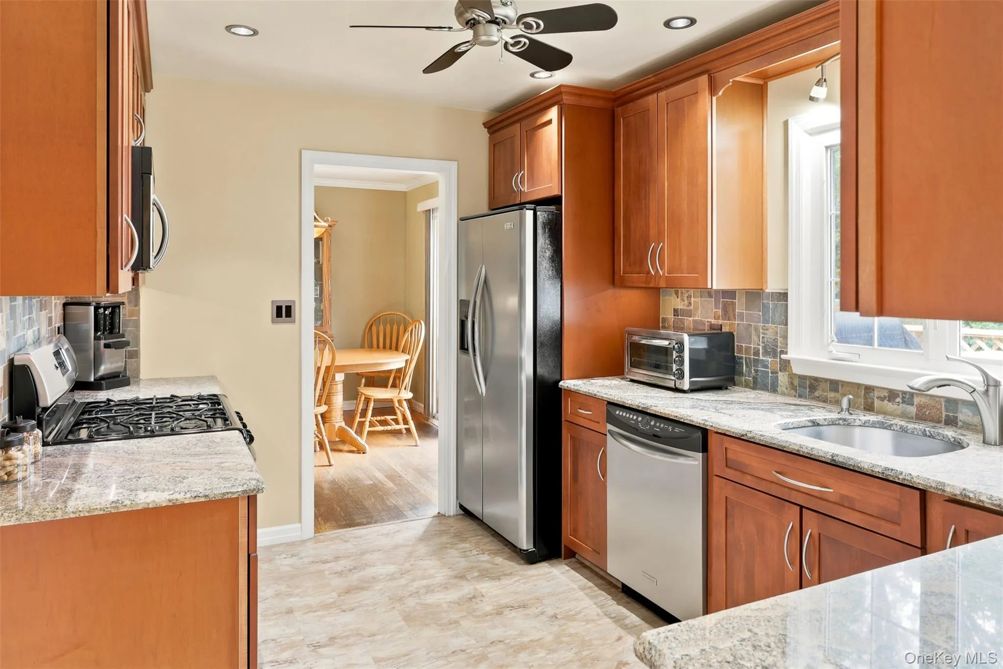 Kitchen featuring wood cabinetry, stainless steel appliances, granite countertops, and a tiled backsplash Kitchen featuring wood cabinetry, stainless steel appliances, granite countertops, and a tiled backsplash
