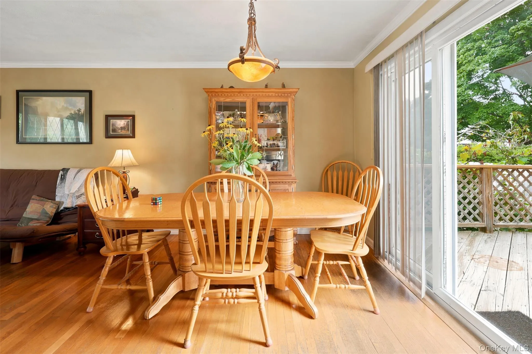 Hardwood flooring throughout featuring crown molding, a built-in display cabinet, and direct access to an exterior deck via sliding glass doors Hardwood flooring throughout featuring crown molding, a built-in display cabinet, and direct access to an exterior deck via sliding glass doors